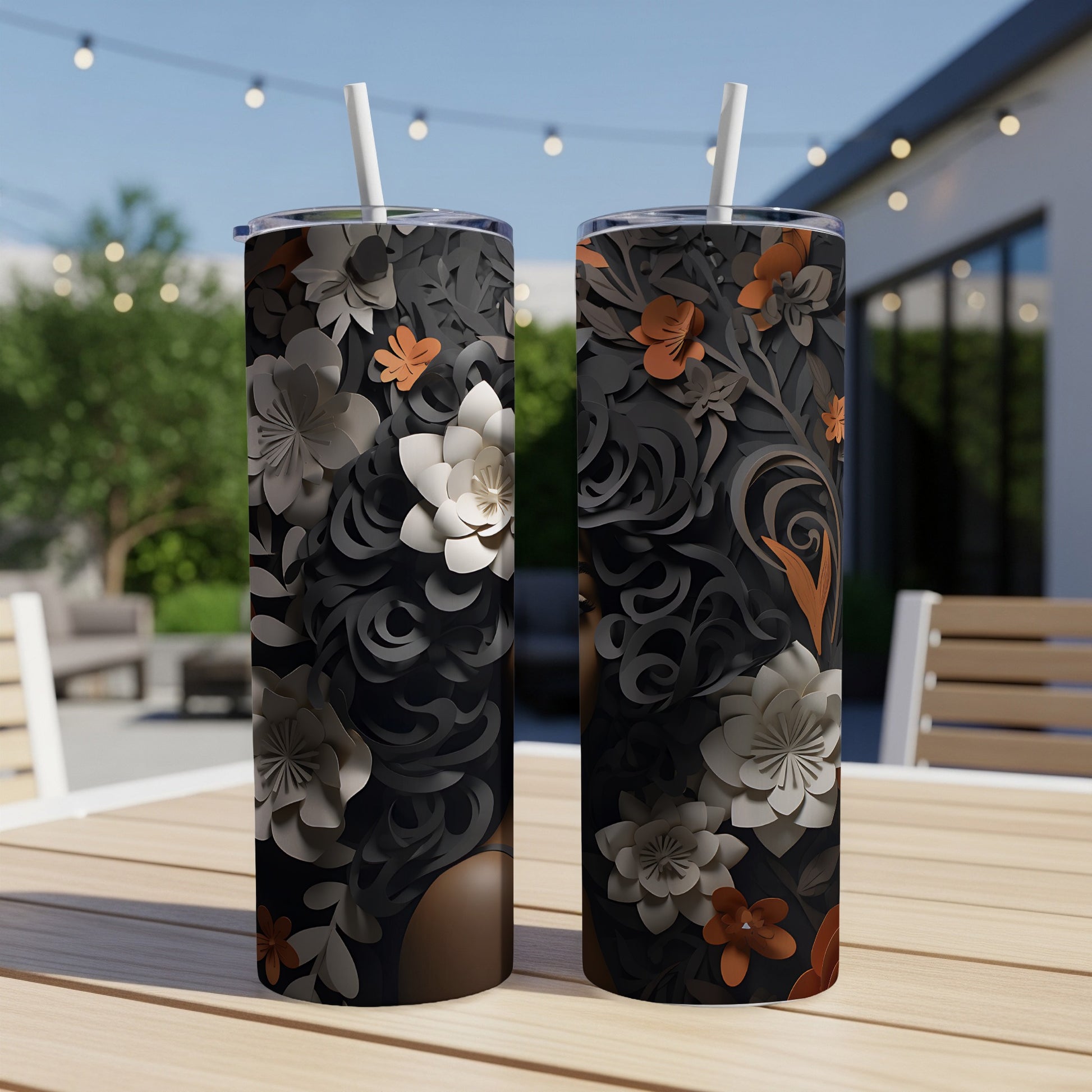 Two tall tumblers with floral designs on a wooden table outdoors.