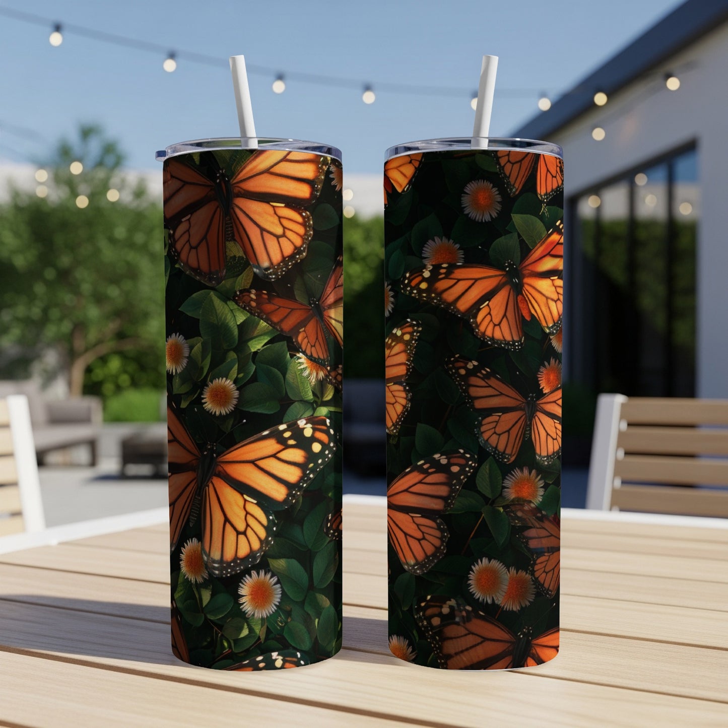 Two tumblers with monarch butterfly and floral pattern on outdoor table.