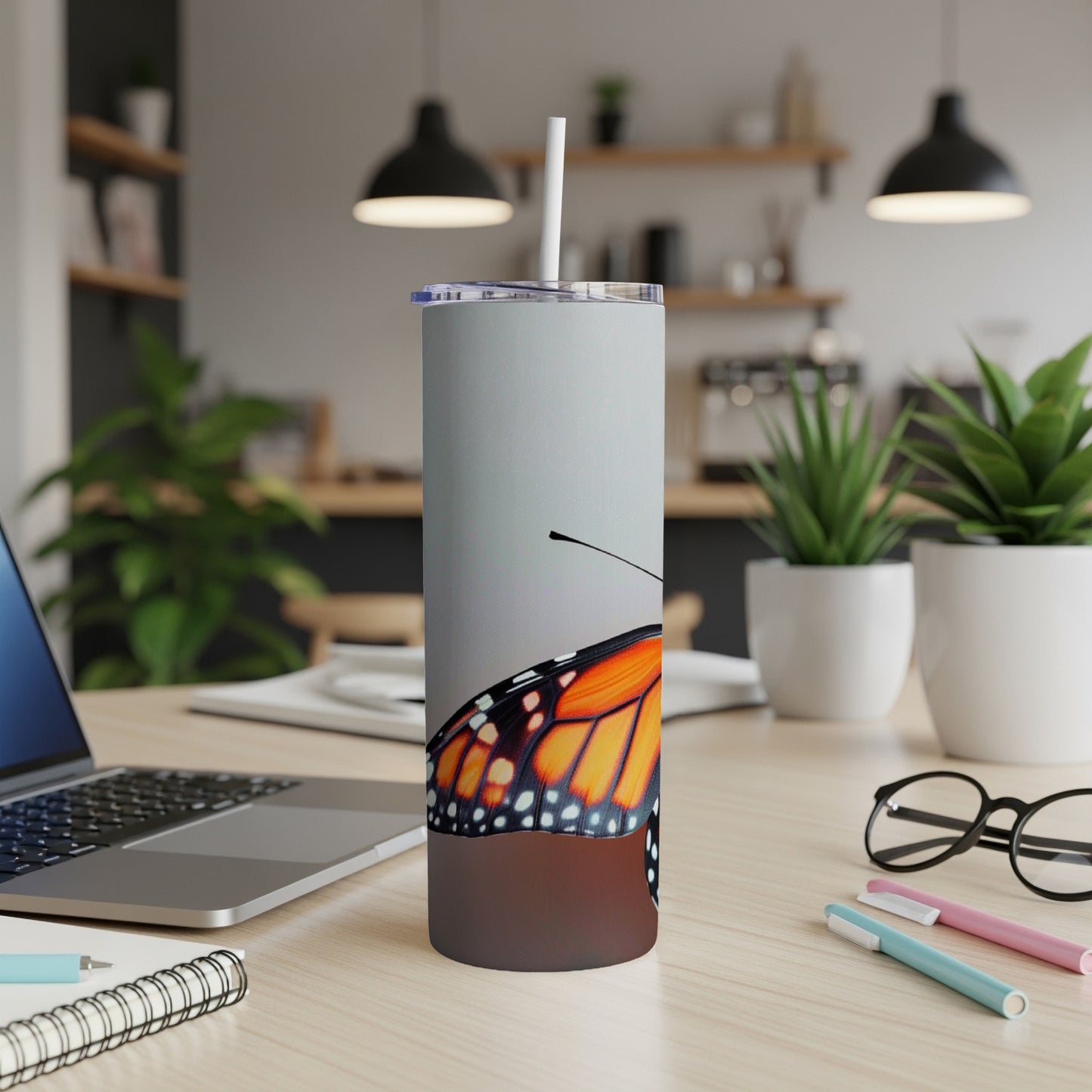 Monarch butterfly wing detail on a white tumbler with a straw.