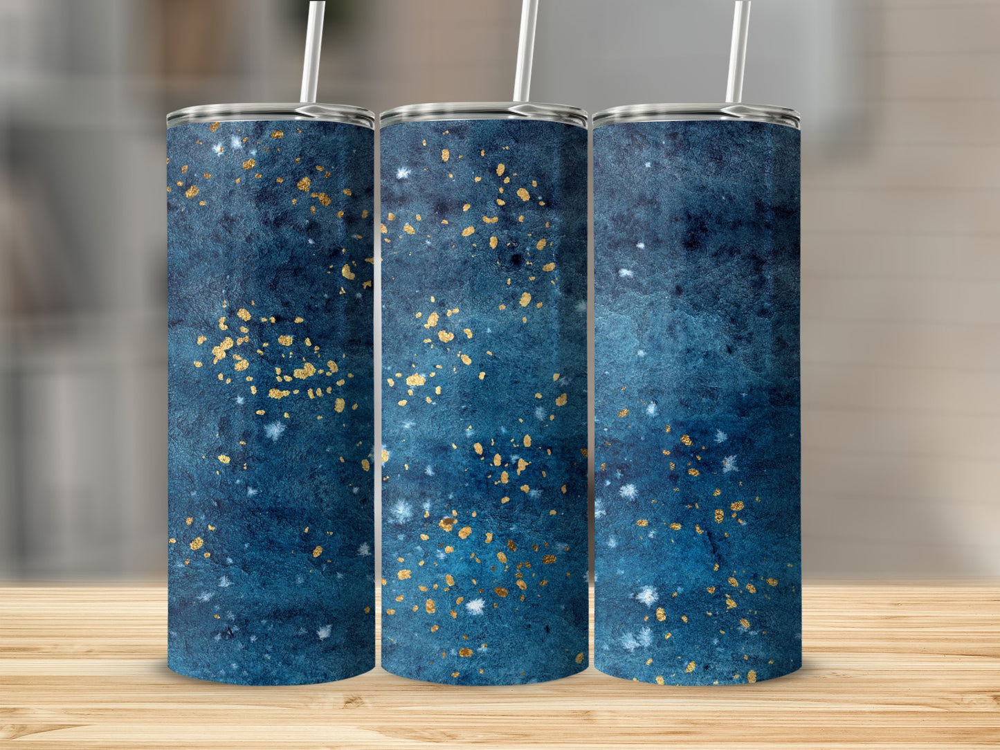 Three tumblers with blue watercolor and gold speckle pattern on wooden surface