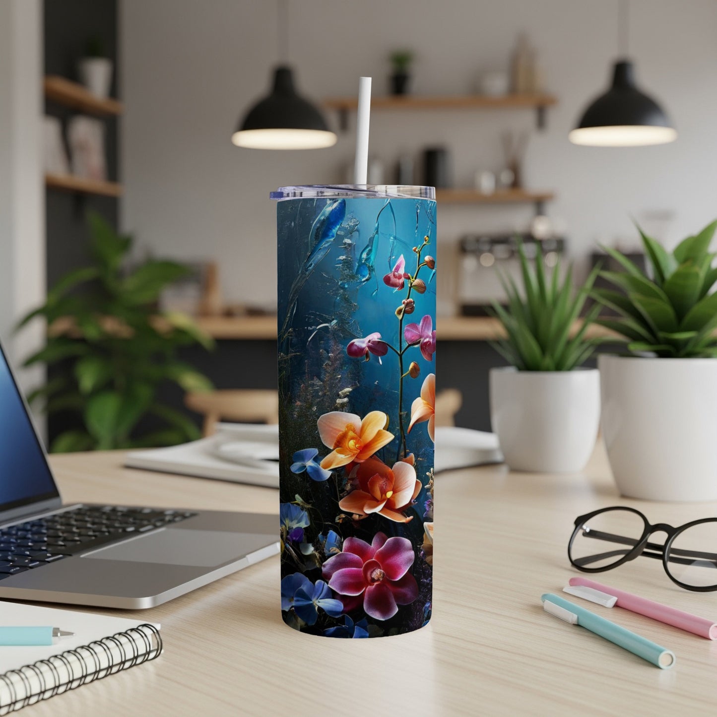 Floral tumbler with orchids and blue background on a desk.