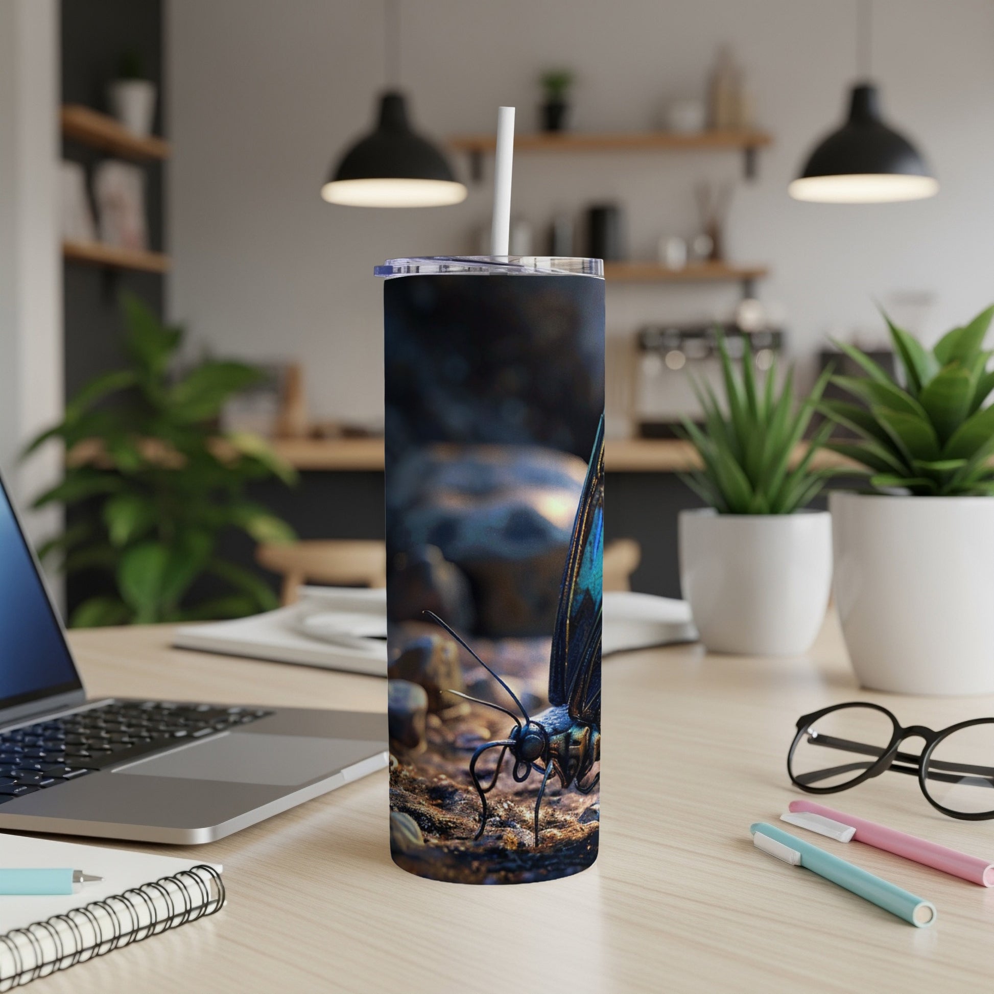Blue and black butterfly design on a tumbler with a straw, on a desk.