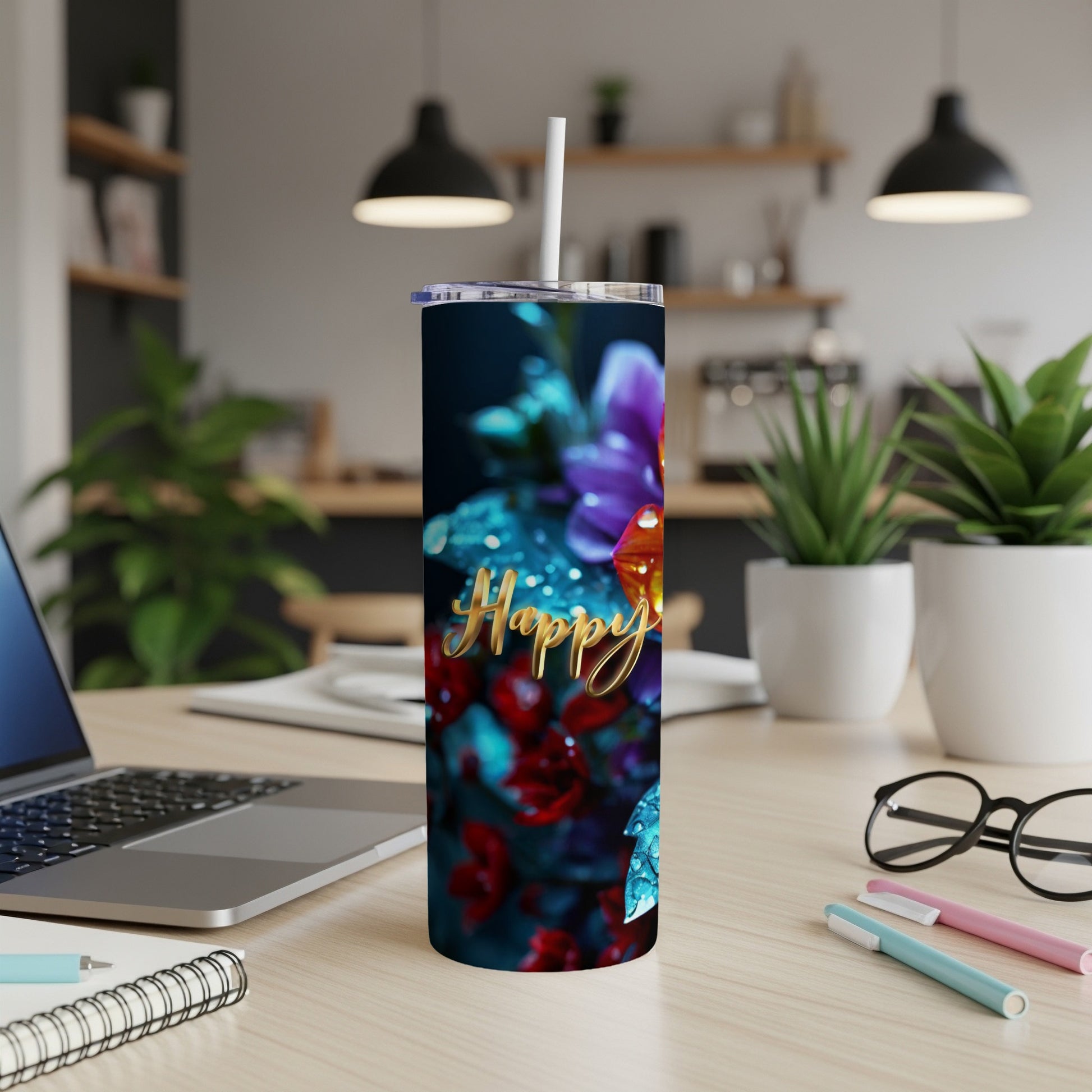 Tumbler with "Happy" text and floral design on desk with laptop.
