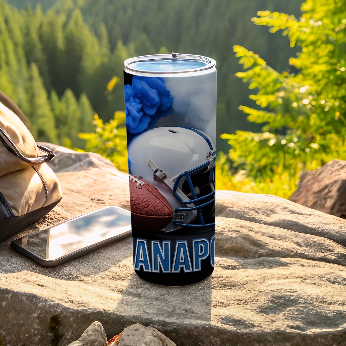 Tumbler with football, helmet, and "ANAPO" text on a rocky outdoor surface.