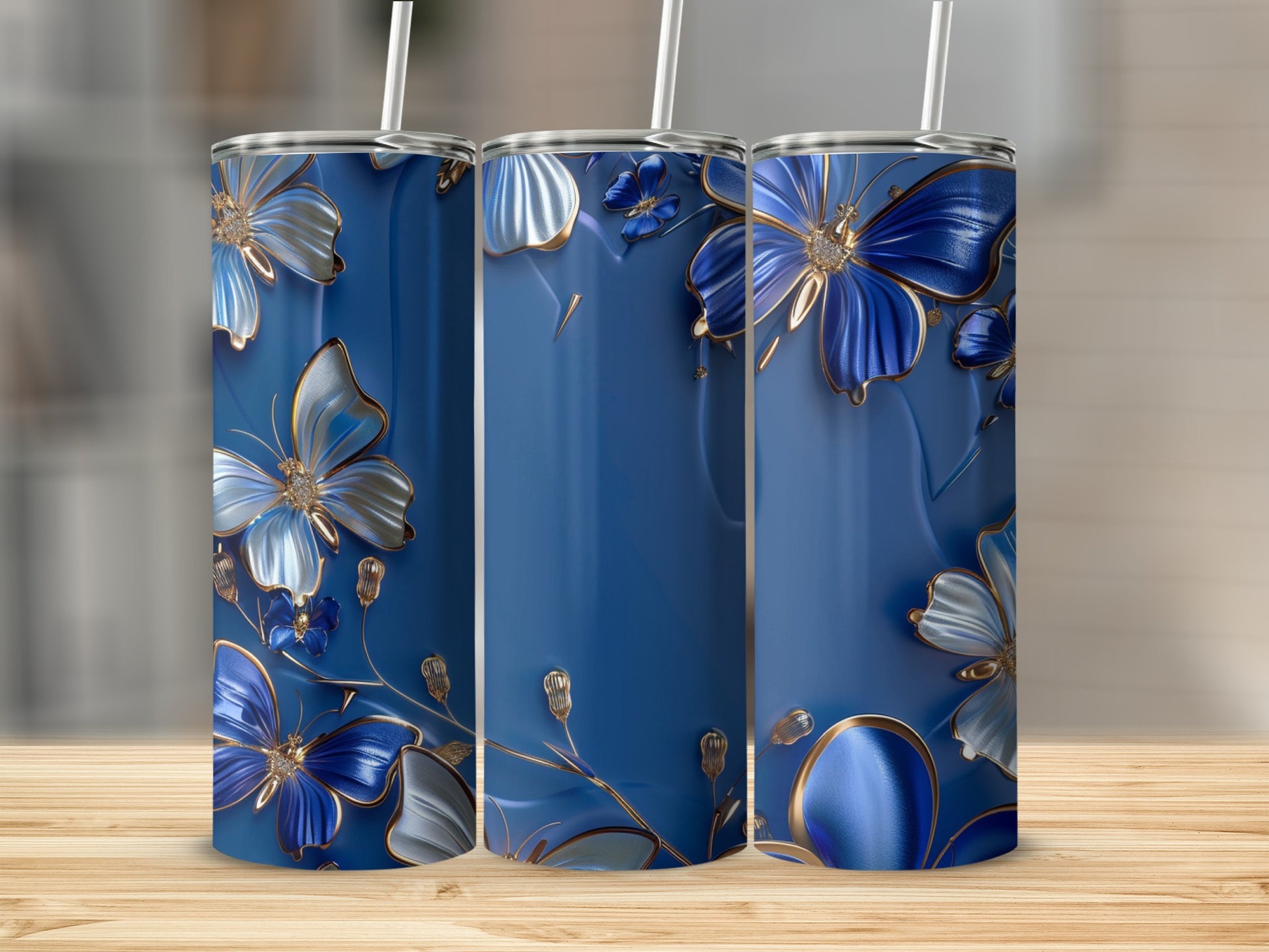 Three blue tumblers with raised gold and blue floral and butterfly designs.