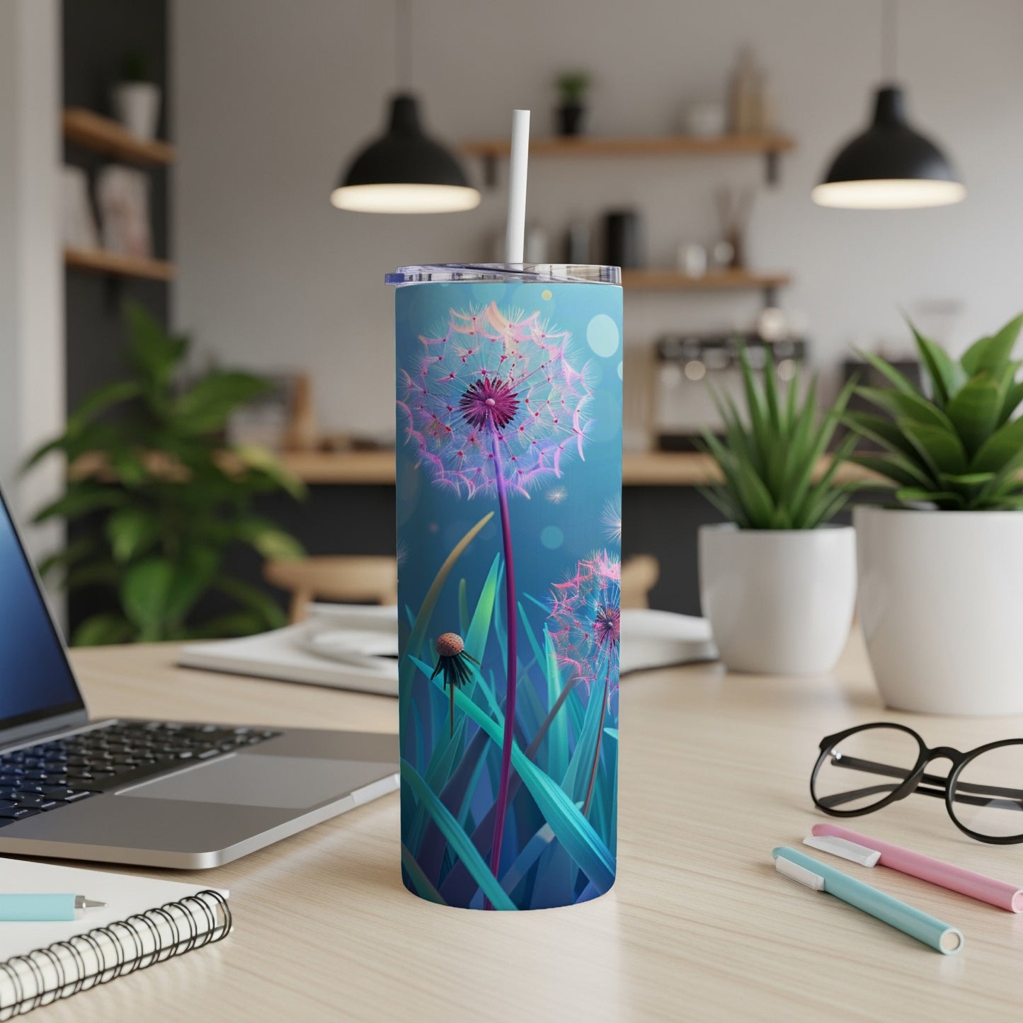 Blue tumbler with dandelion design and straw on a desk.