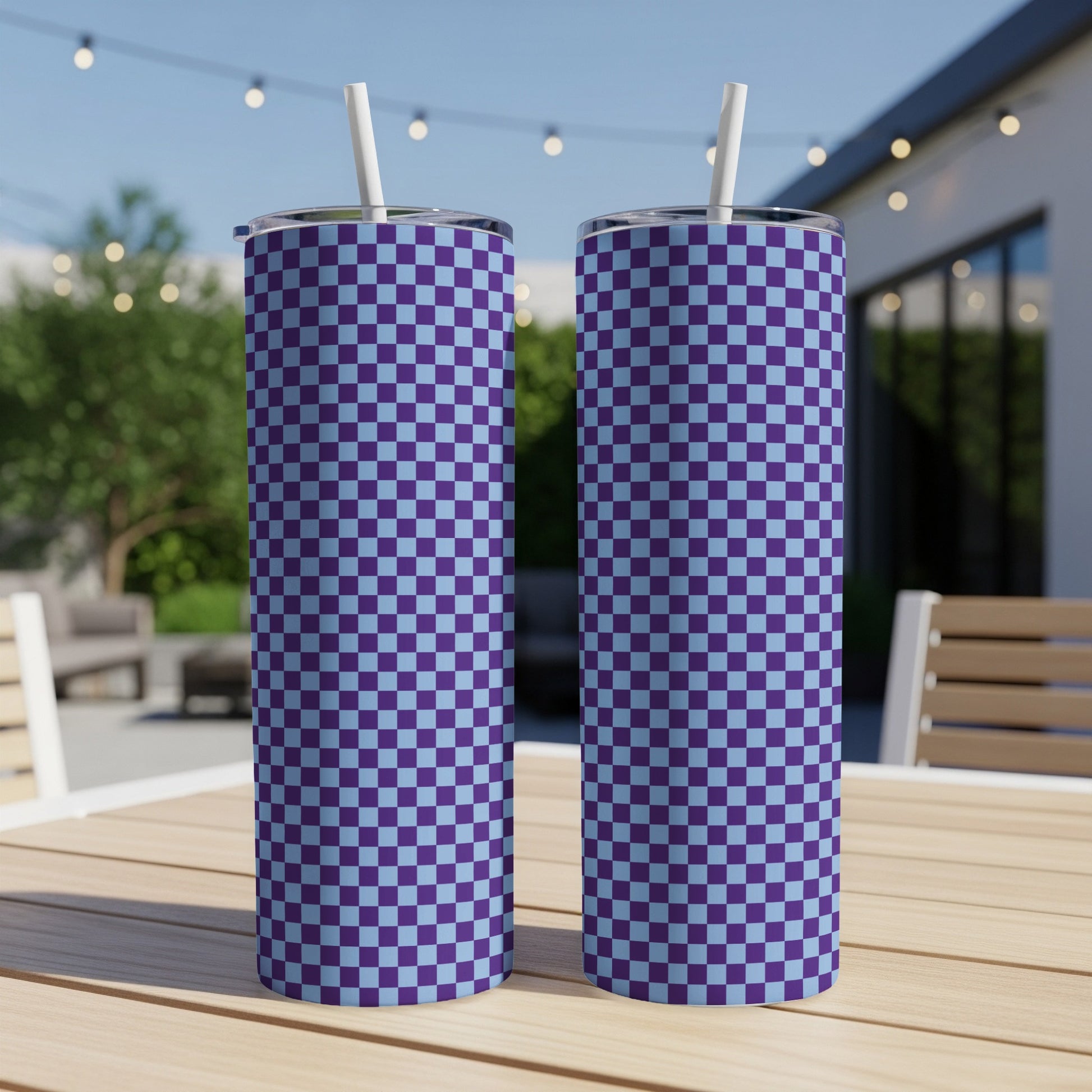 Two tall tumblers with a blue and purple checkered pattern stand on a table outdoors.