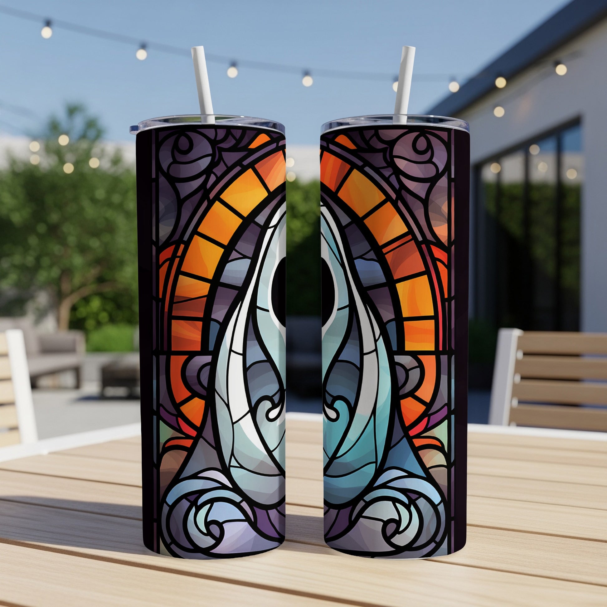 Two stained-glass pattern tumblers with straws on a table.