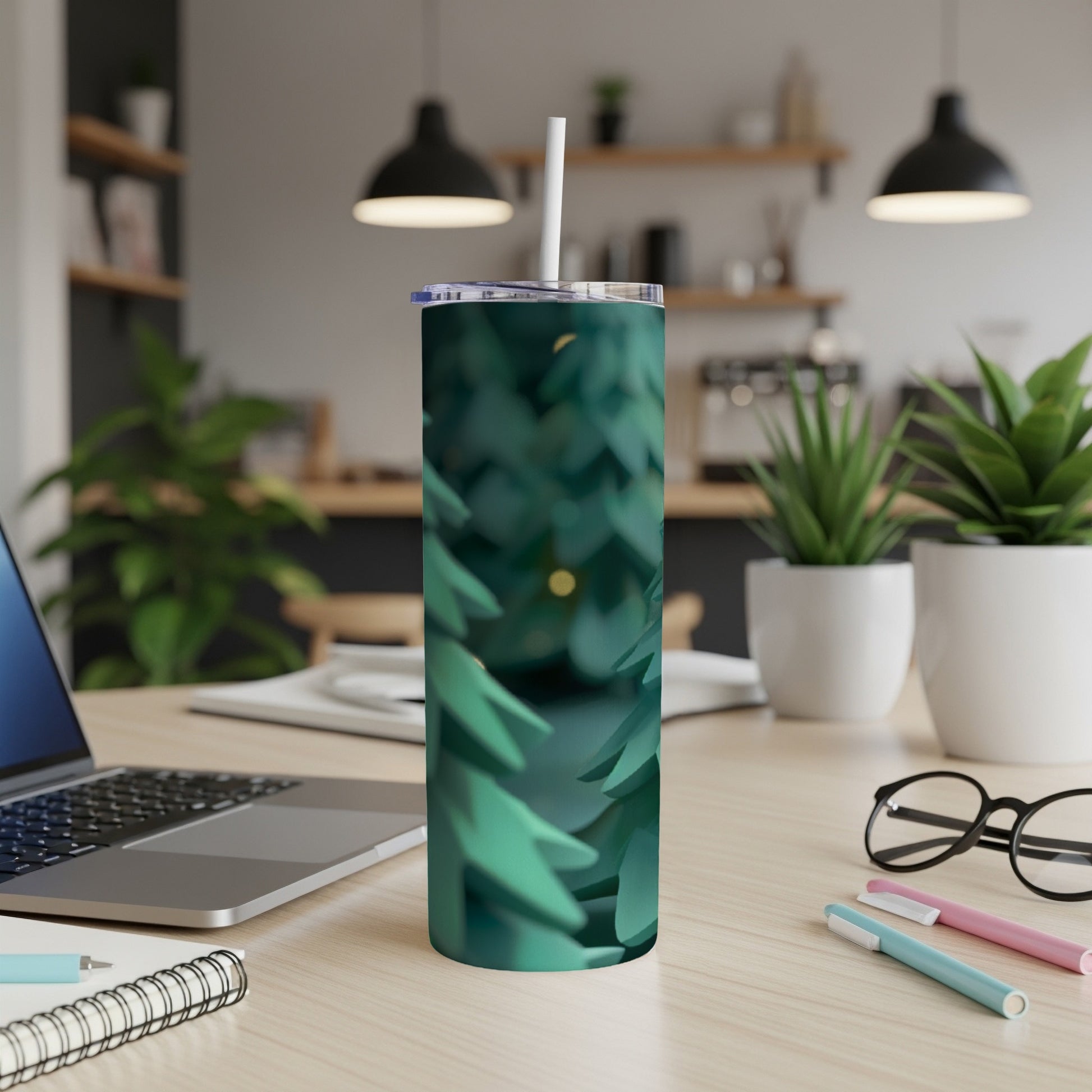 Green pine needles cover a stainless steel tumbler on a desk.