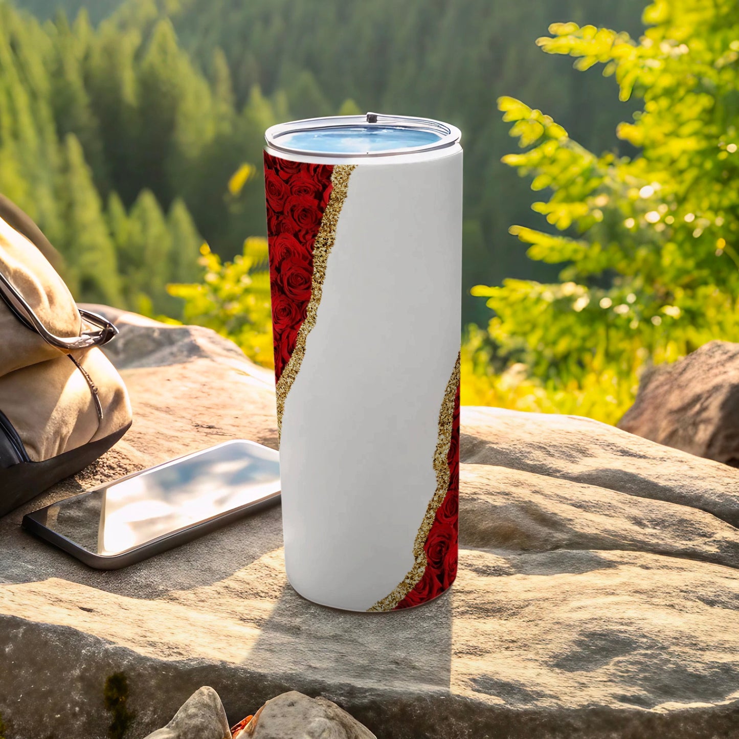 White tumbler with red rose and gold glitter pattern, phone, and backpack.