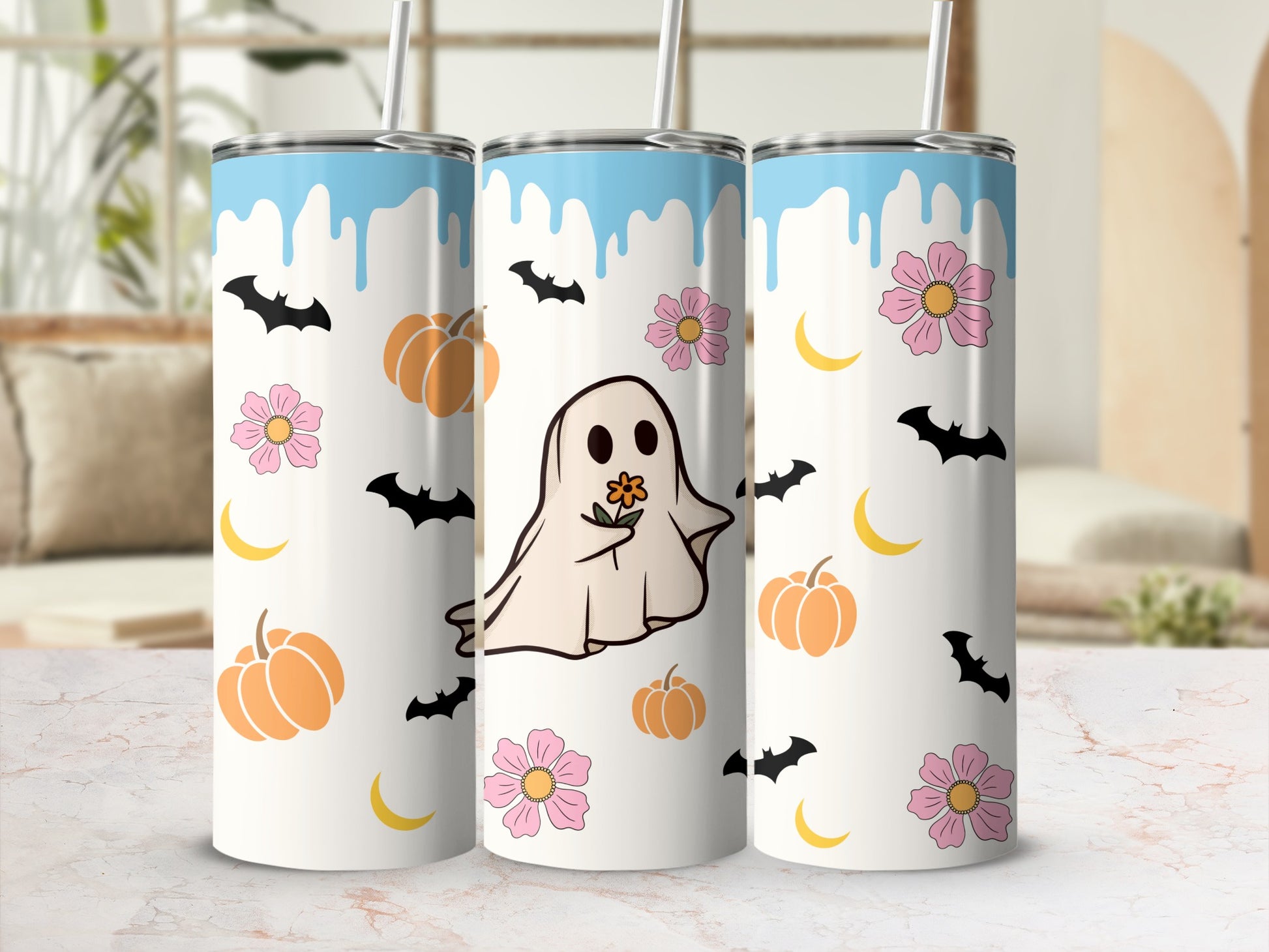 Three tumblers with ghost, pumpkin, bat, and flower Halloween designs.