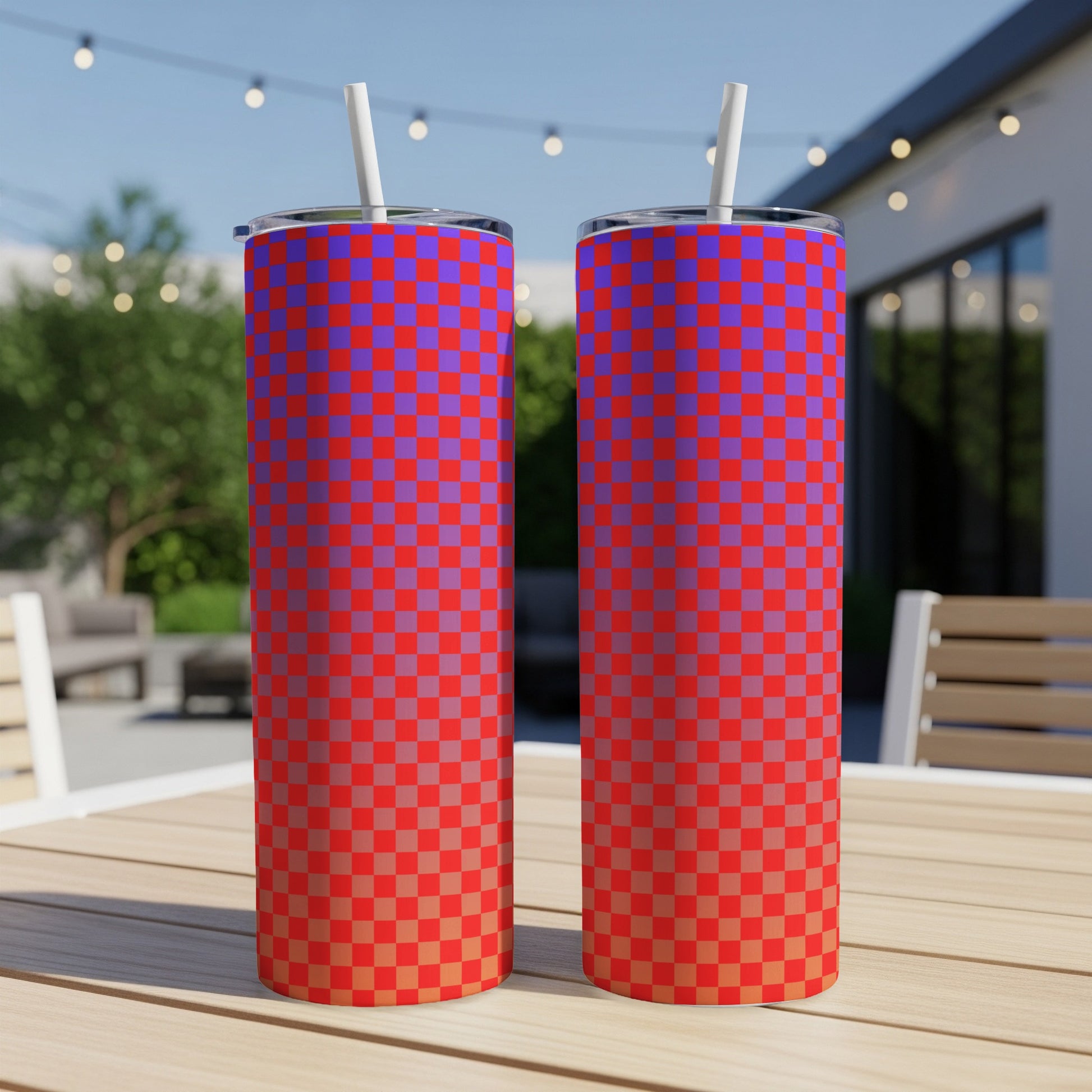 Two tall tumblers with red and blue checkerboard pattern, on a table outdoors.
