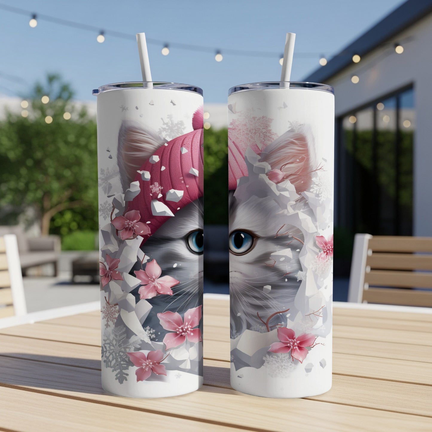 Two tumblers with a close-up of a cat wearing a pink beanie, surrounded by pink flowers and snowflakes.