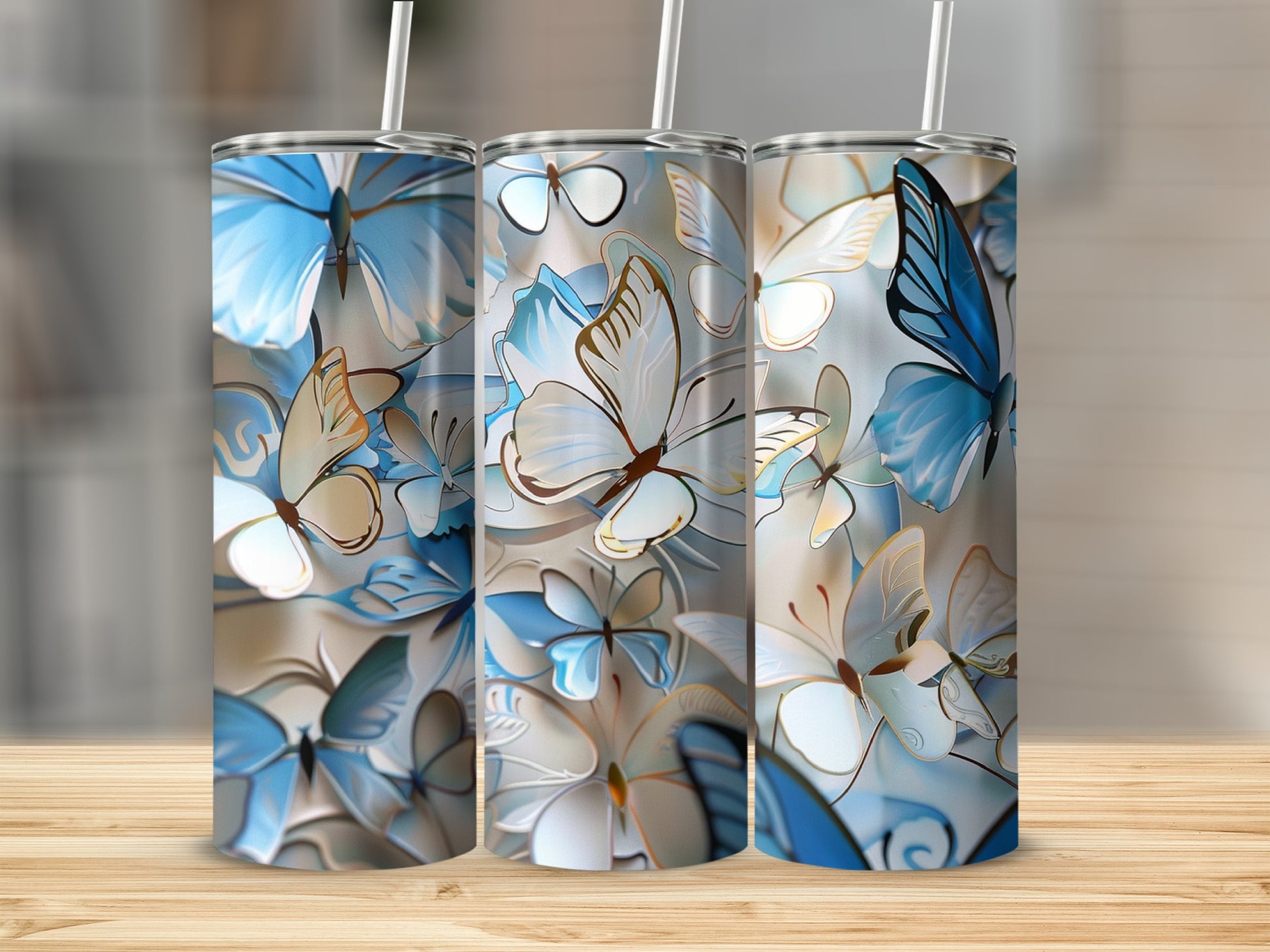 Three tumblers with a blue and gold butterfly design on a wooden surface.