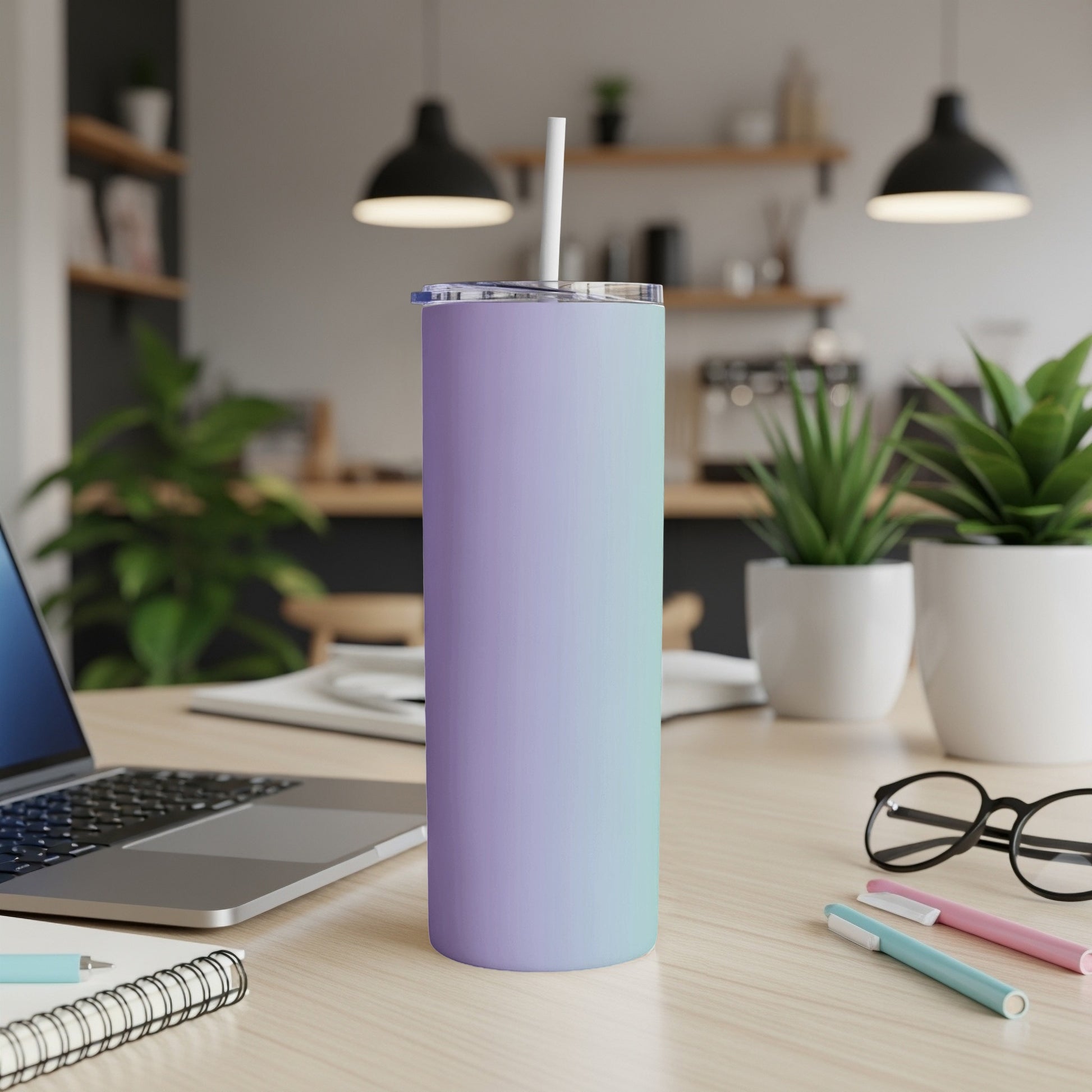Gradient purple and teal tumbler with straw on a desk.