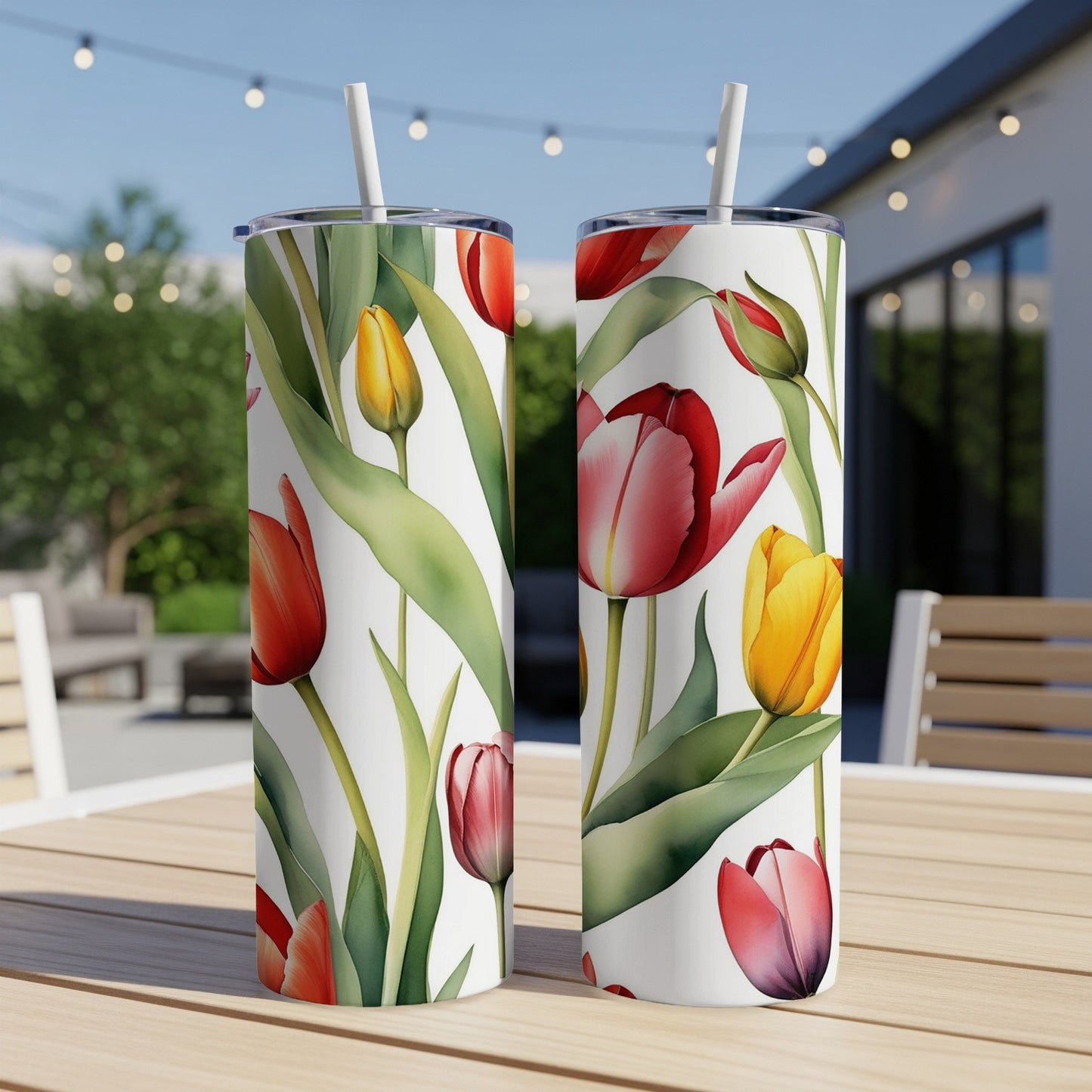 Two tumblers with red and yellow tulips and green leaves on a table.