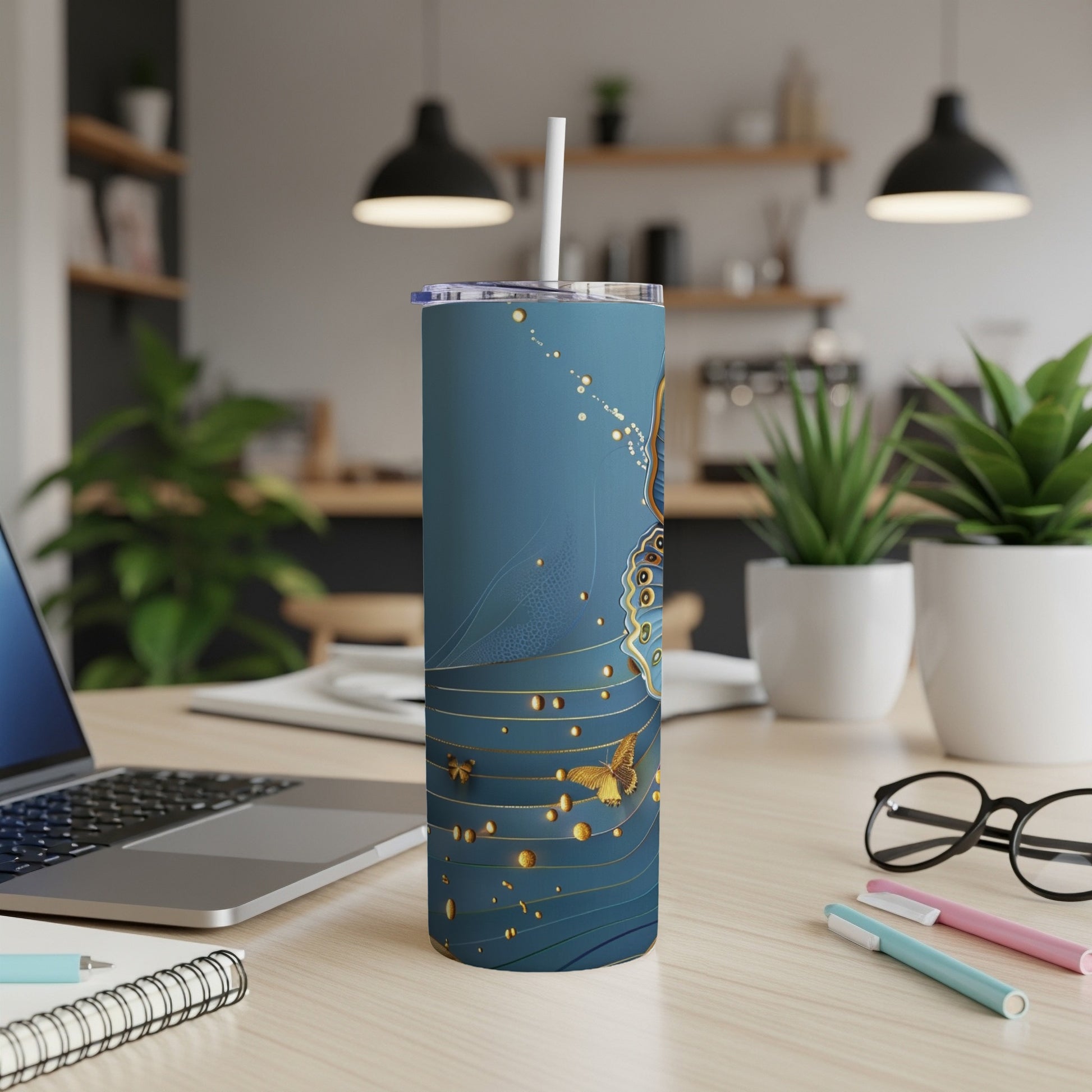 Blue tumbler with gold butterfly and floral pattern on desk.