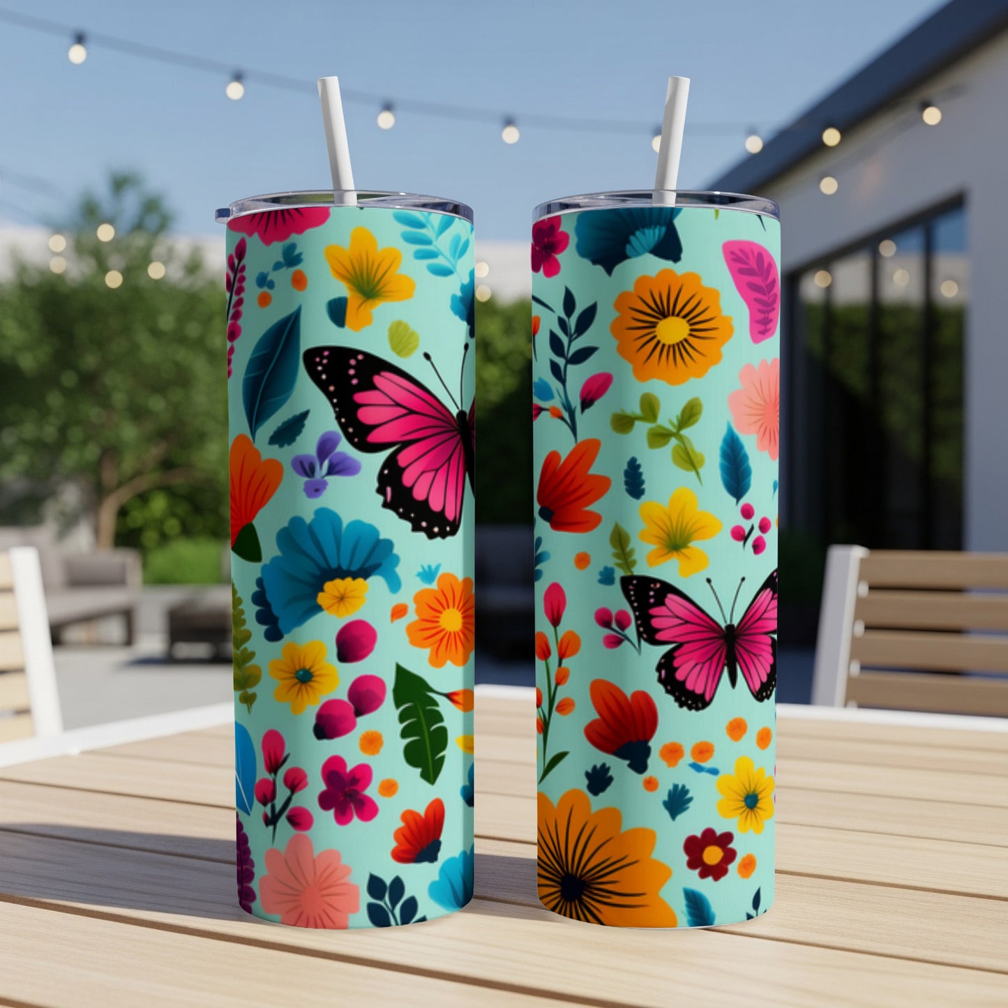 Two teal tumblers with colorful floral and butterfly patterns, outdoors.