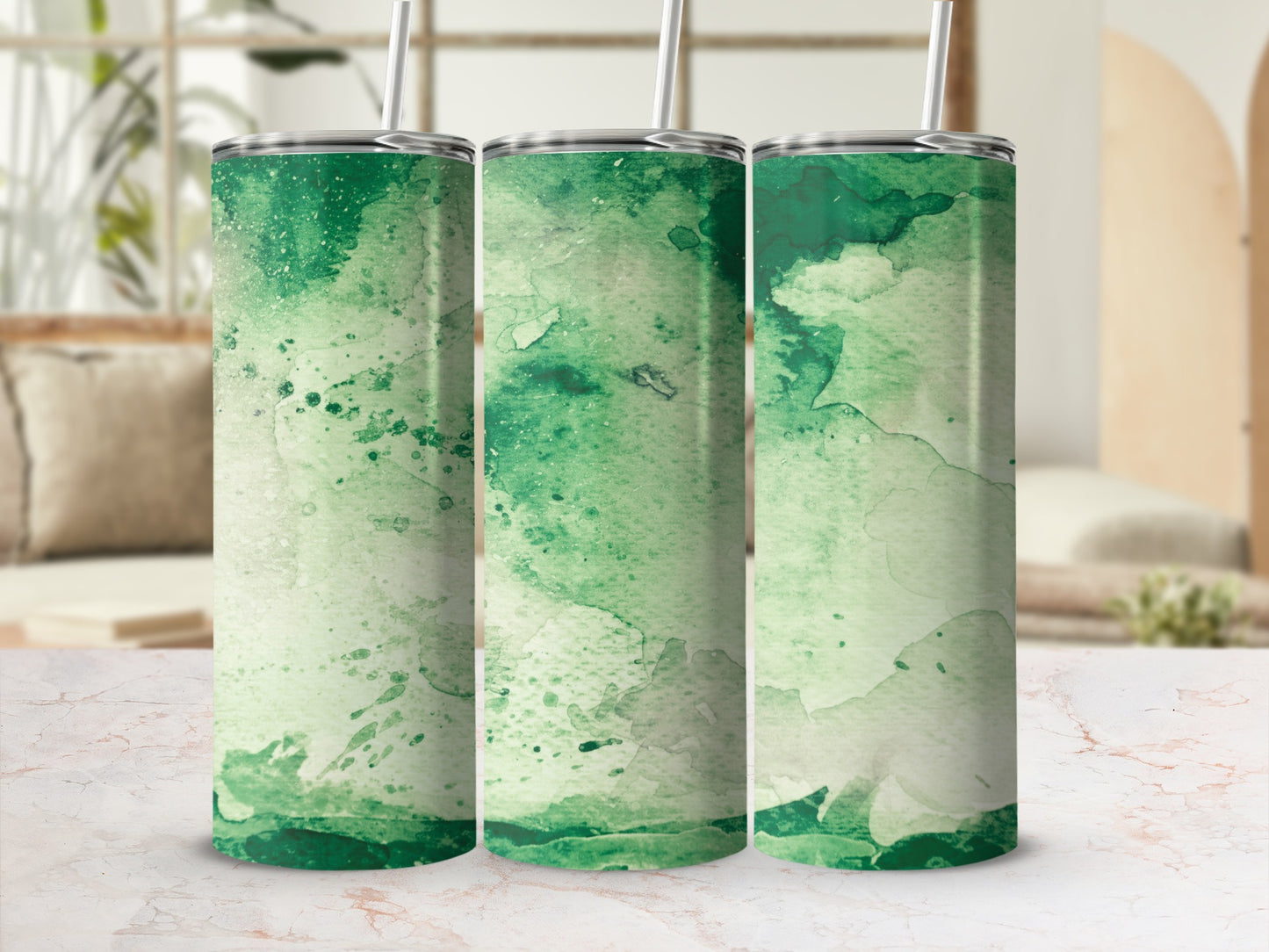Three green watercolor tumblers with straws displayed on a marble surface.