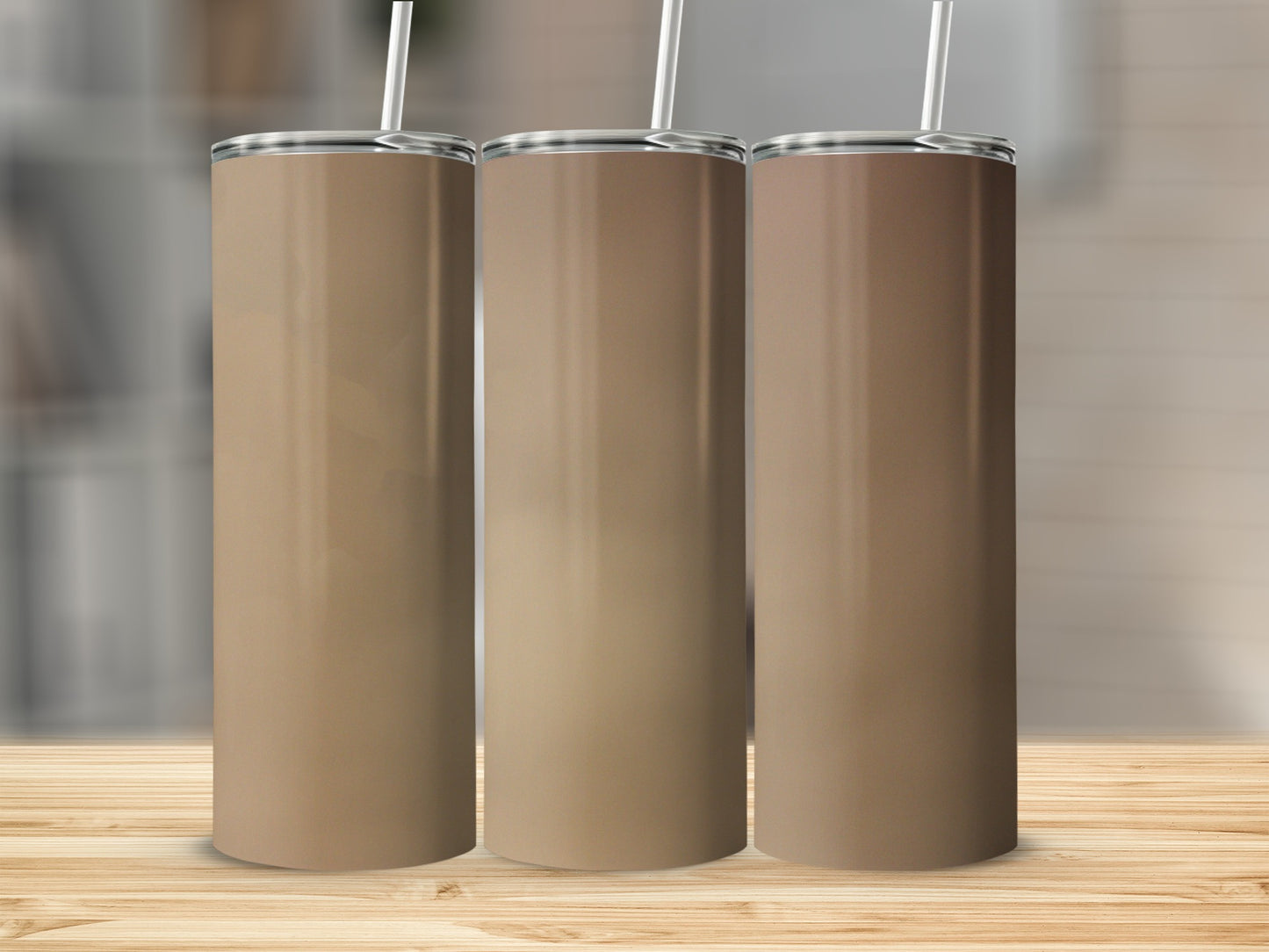 Three blank tan tumblers with straws on a wooden surface.