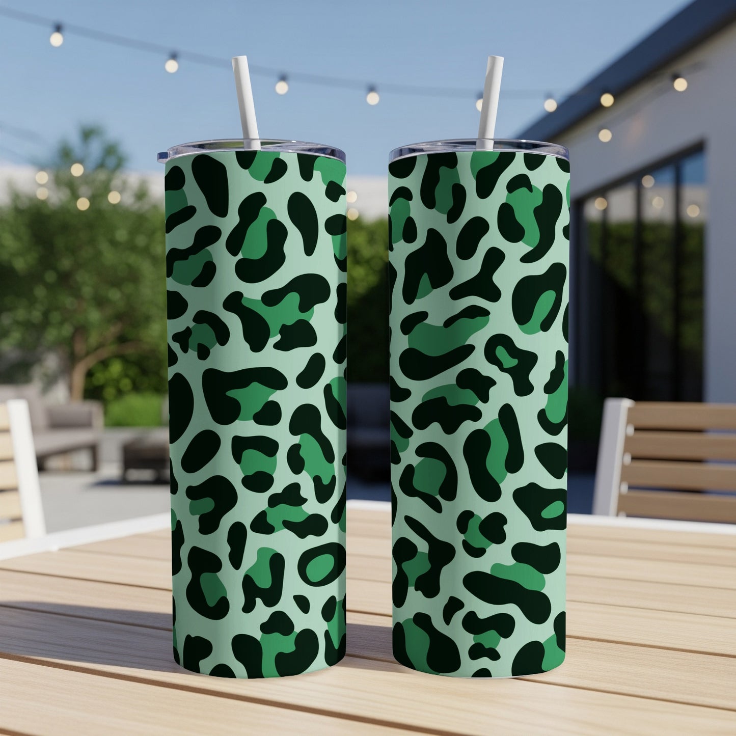 Two green leopard print tumblers with white straws on a table.