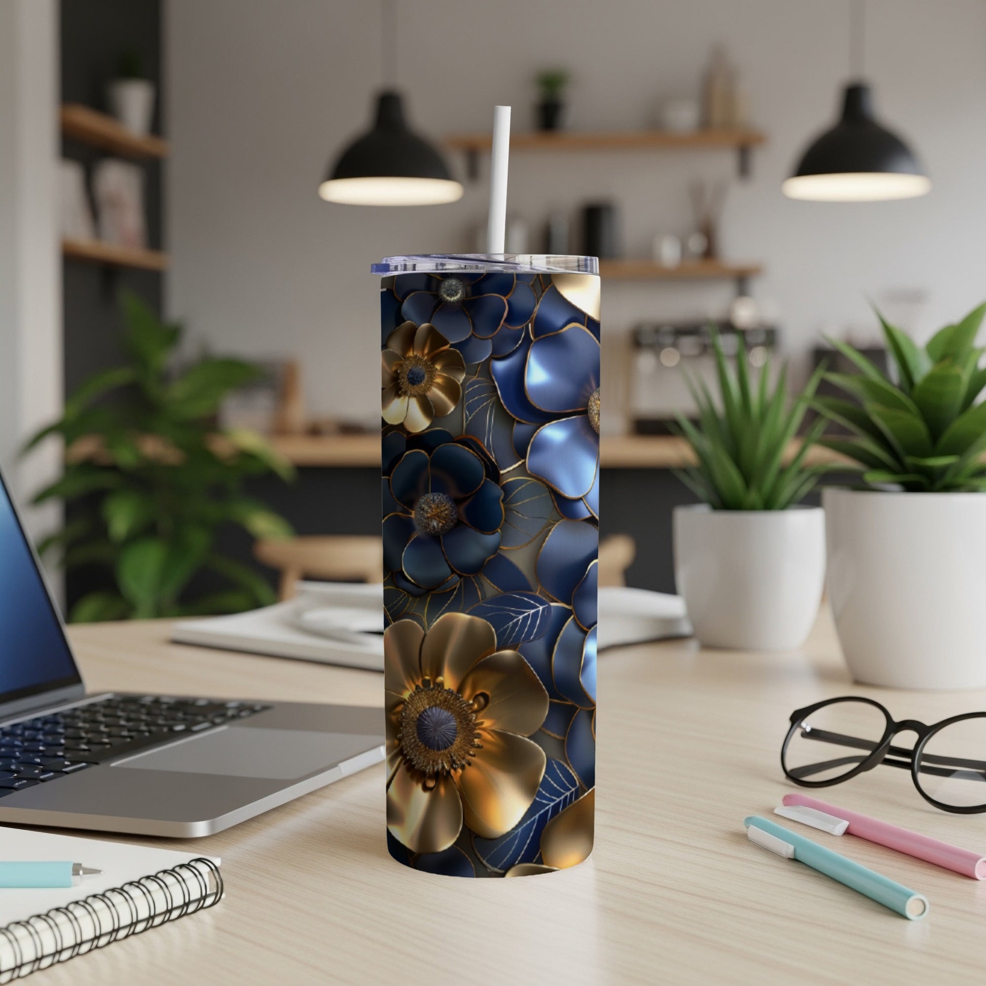 Blue and gold floral patterned tumbler on a desk with a laptop and pens.