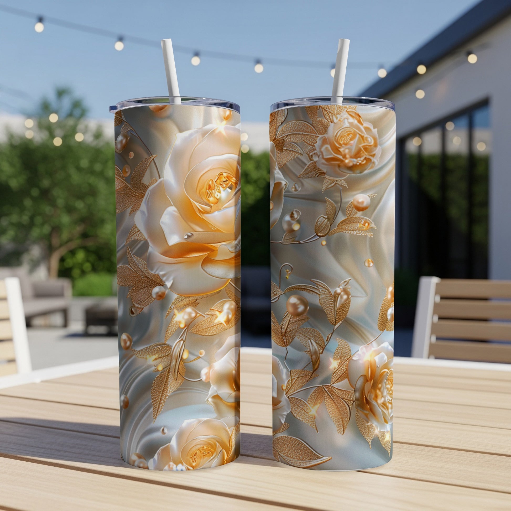 Two tall tumblers with a rose and pearl floral design on a table.