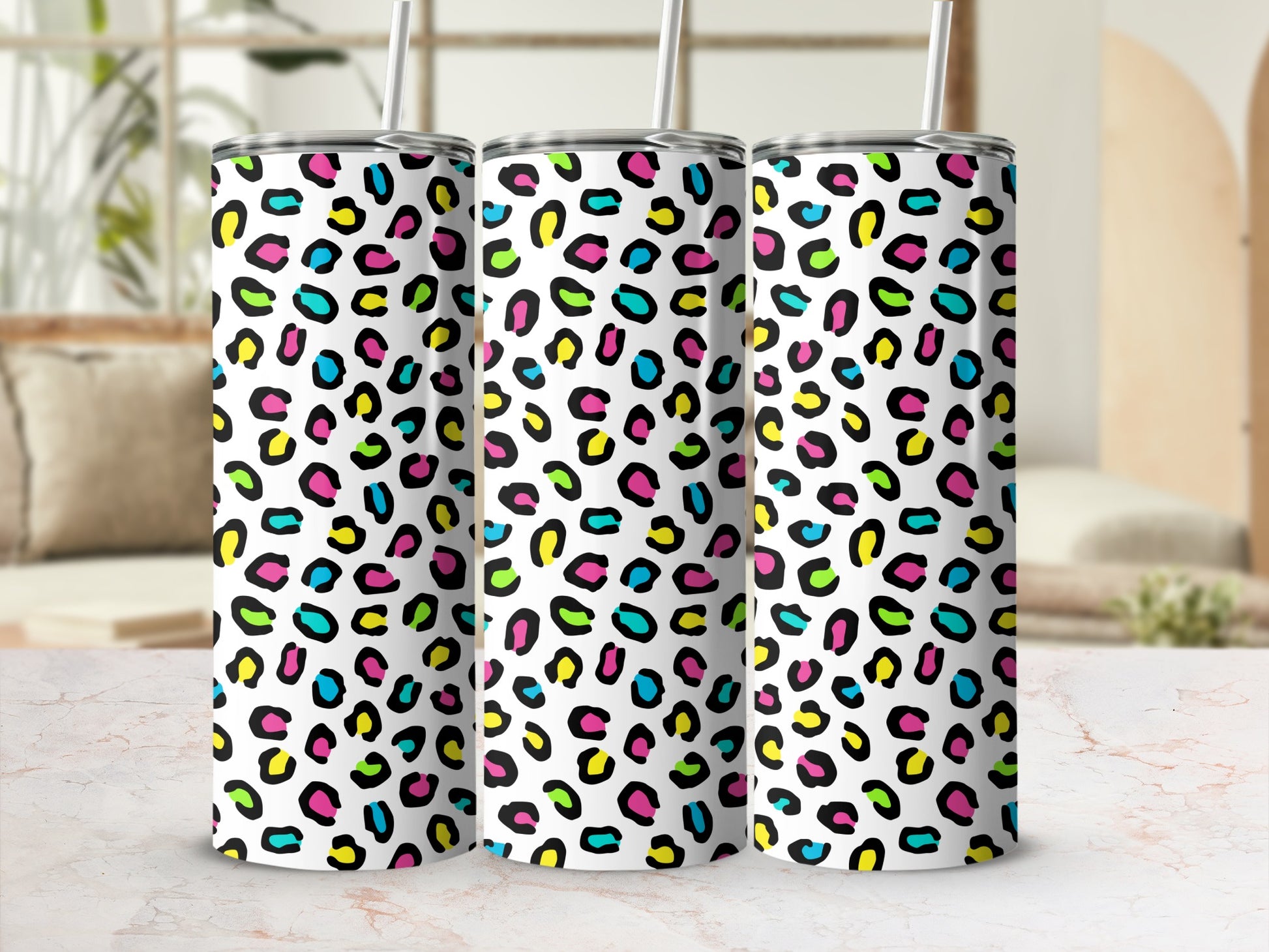 Three white tumblers with a colorful leopard print pattern and straws.