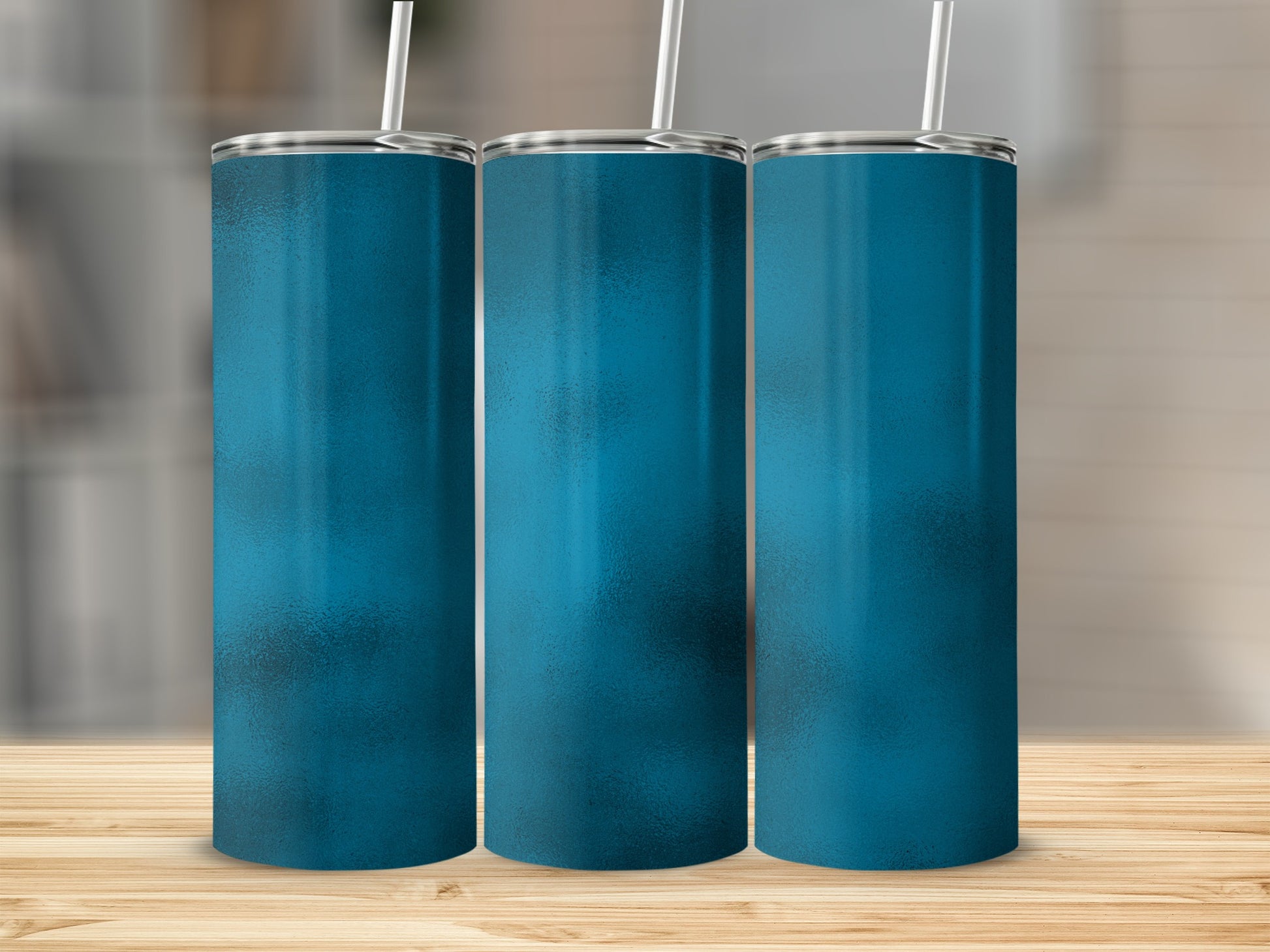 Three blue tumblers with silver lids and white straws on a wooden surface.