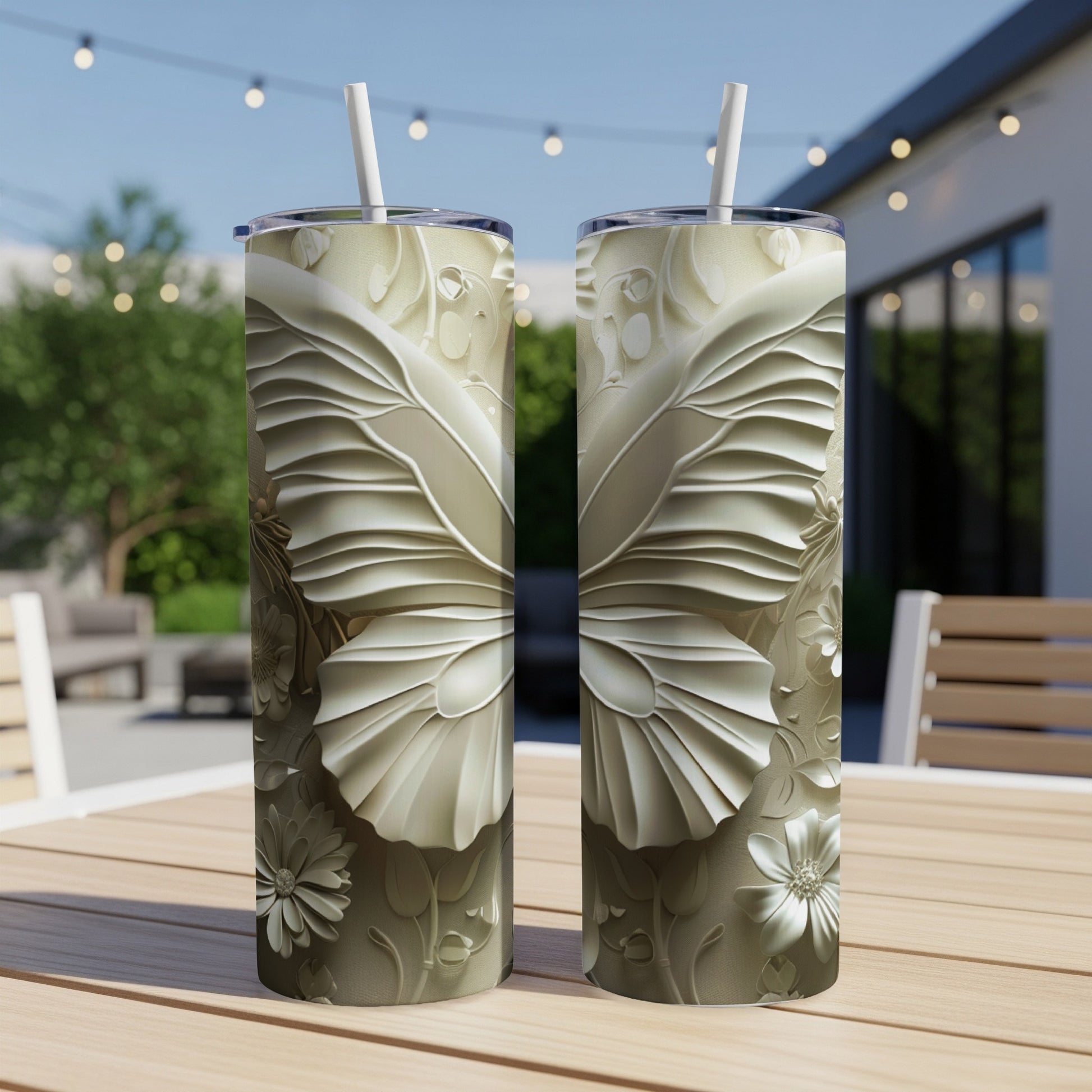 Two tall, tapered tumblers with embossed butterfly and floral designs on a table.