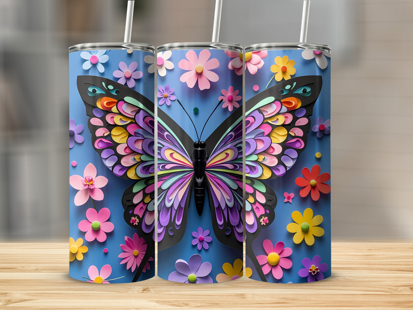 Three tumblers with colorful butterfly and flower designs on blue background