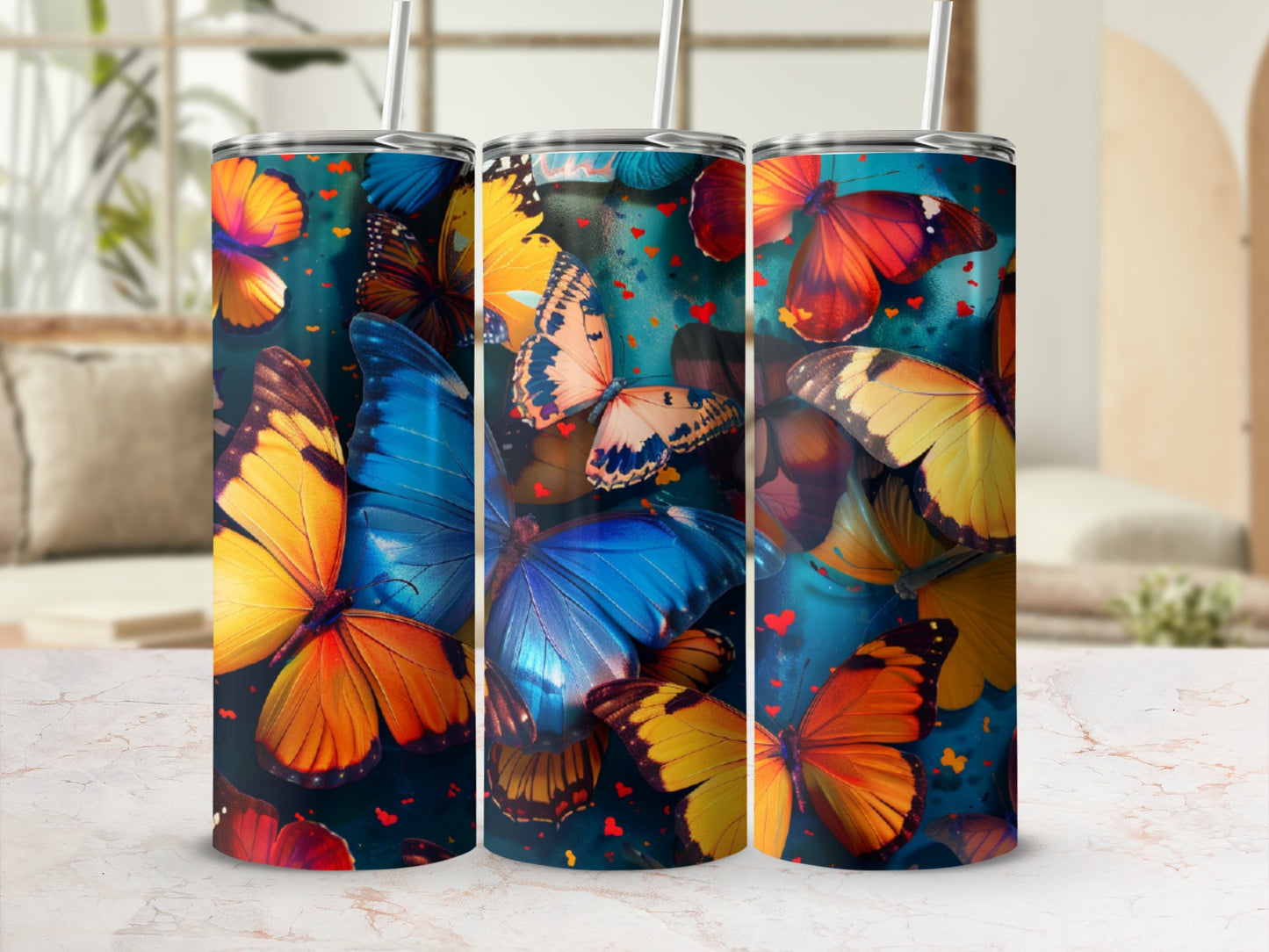Three tumblers adorned with vibrant, overlapping butterfly designs on a marble surface.