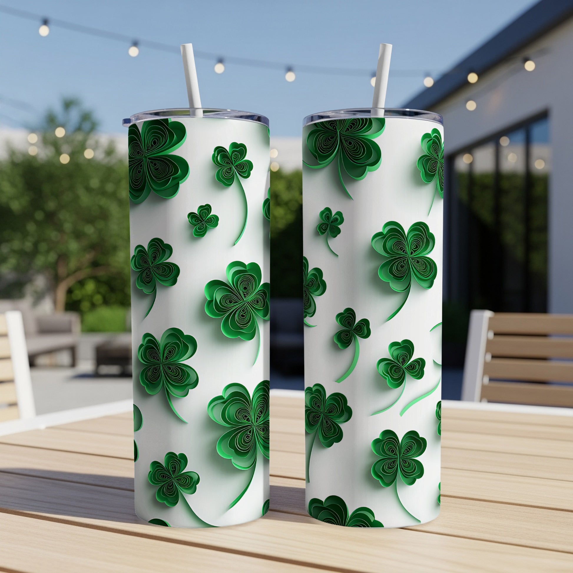 Two white tumblers with green shamrock pattern and straws on a table.