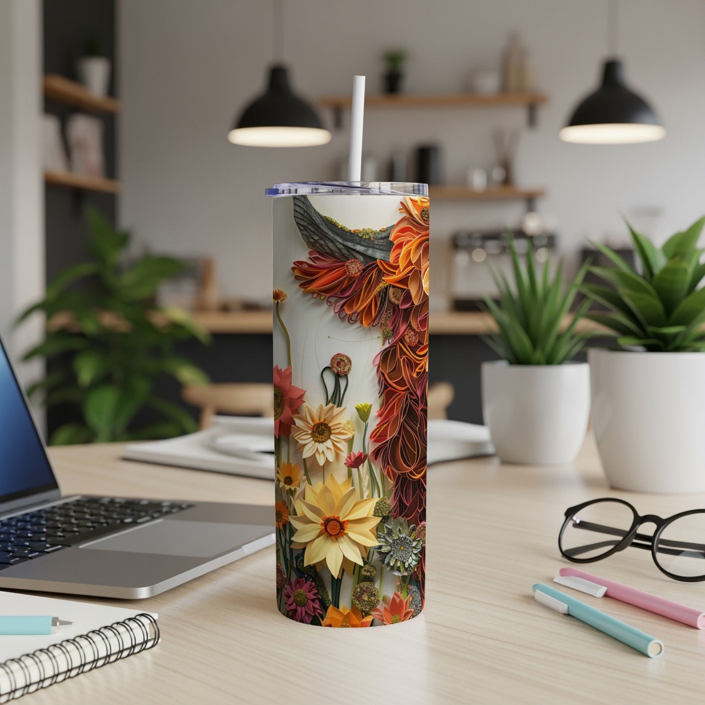 Floral pattern tumbler with straw on a wooden desk with laptop.