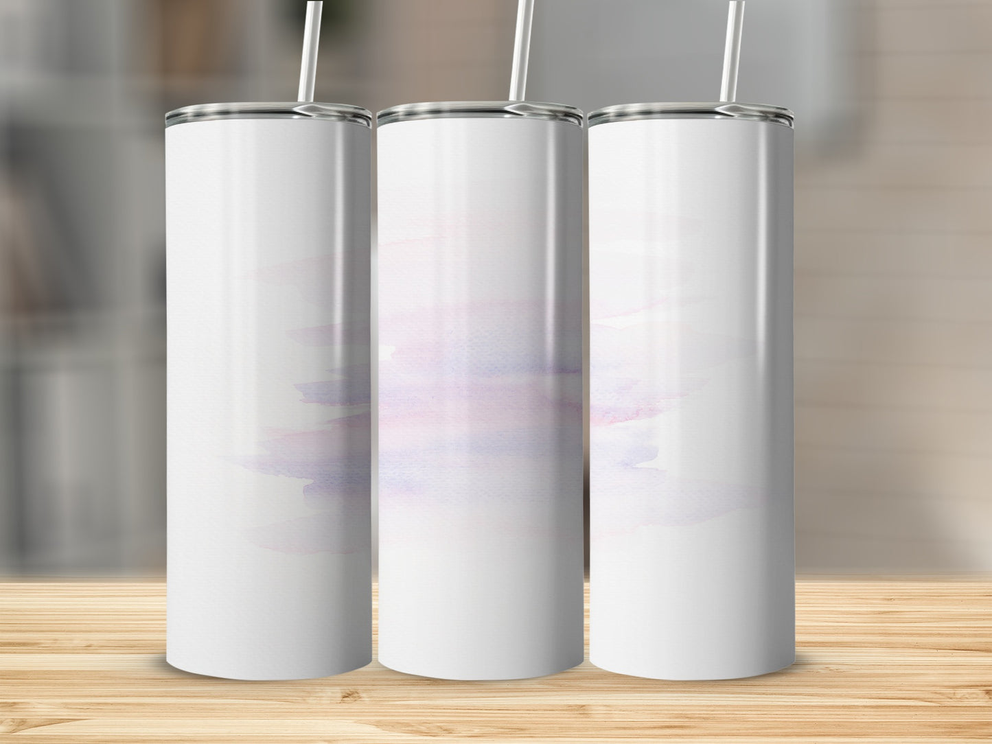 Three blank white tumblers with pastel watercolor wash on a wooden surface.