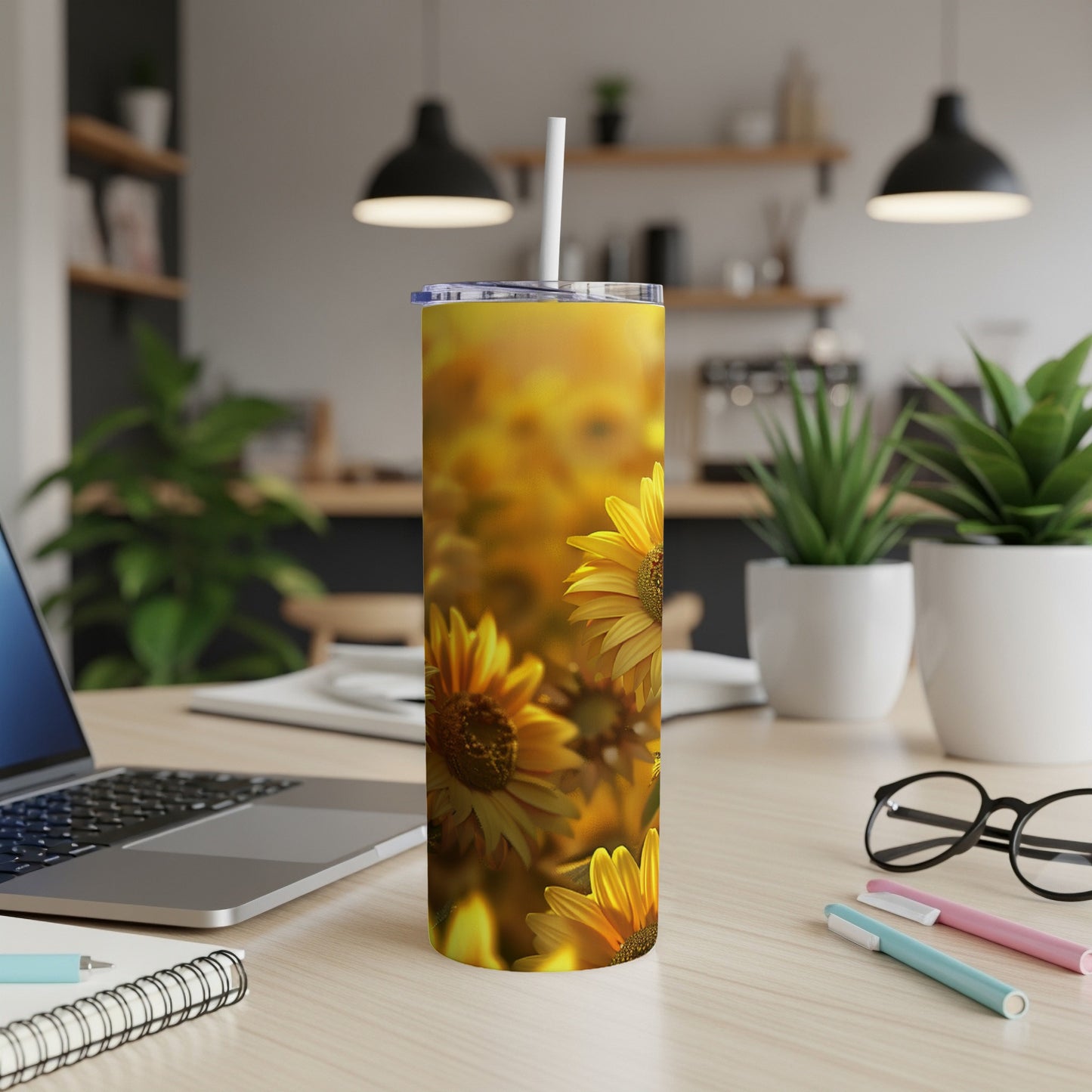 Sunflower print tumbler on a desk with a laptop and pens.