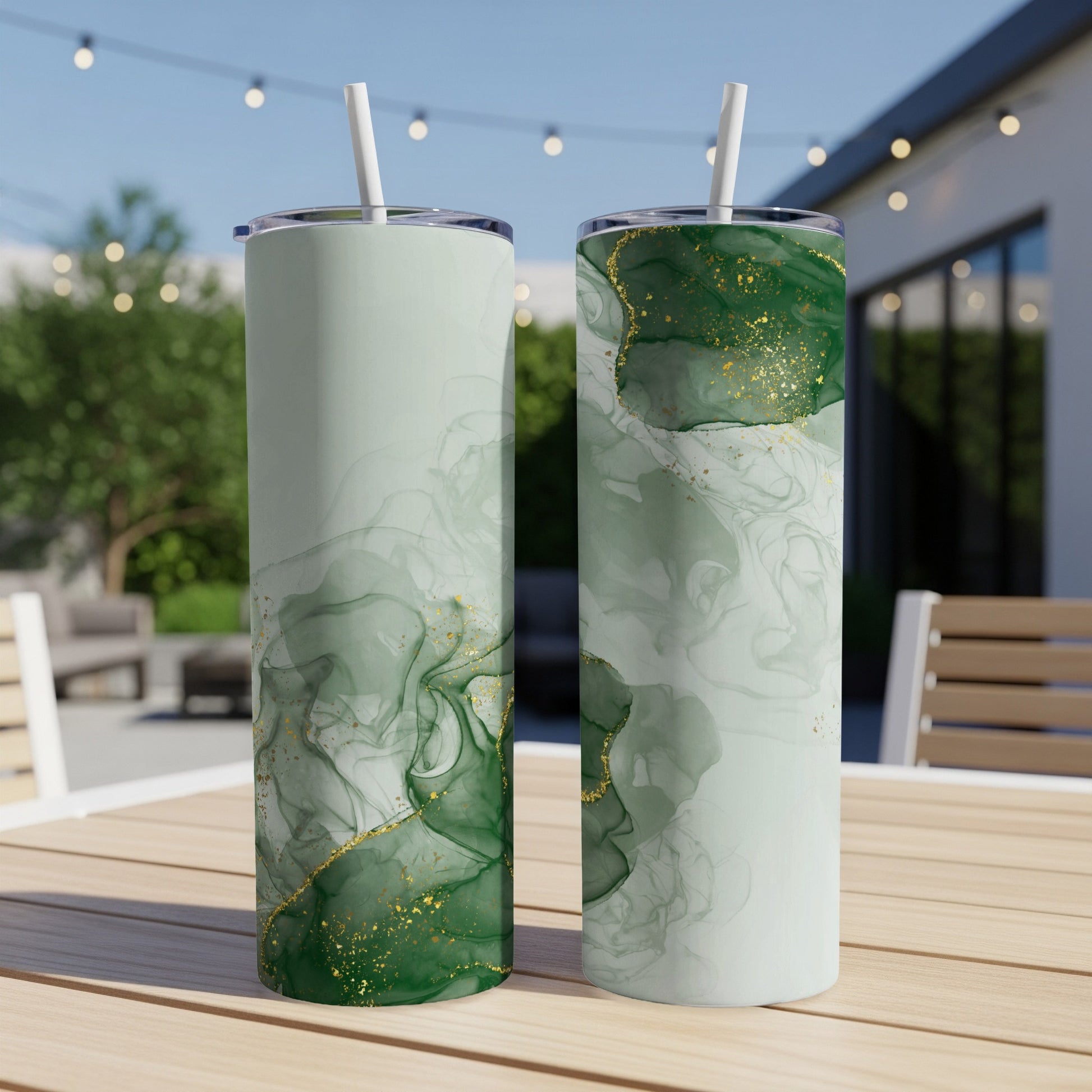 Two tall tumblers with a green and gold abstract marble design on a table.