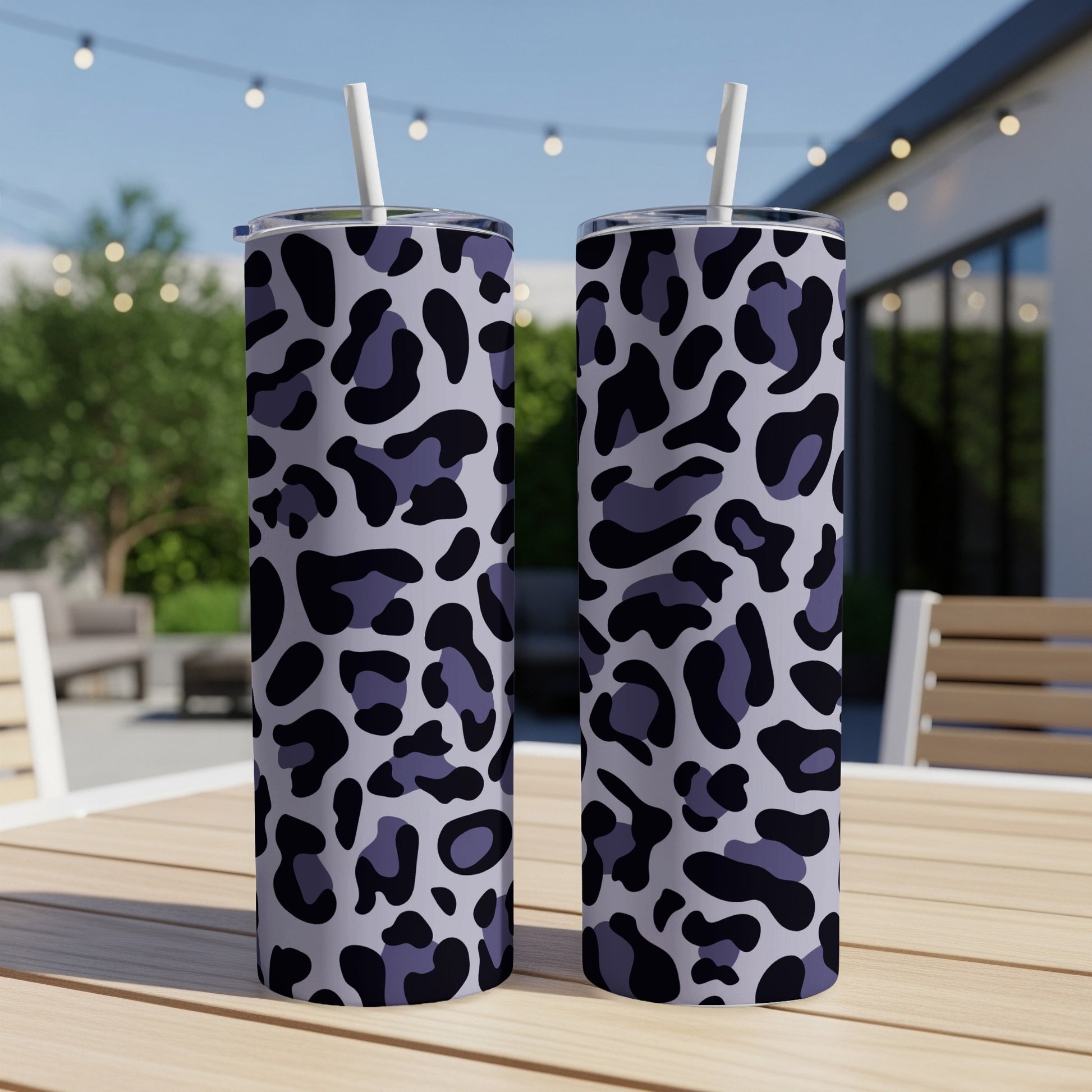 Two tumblers with a purple and black leopard print design sit on a table.