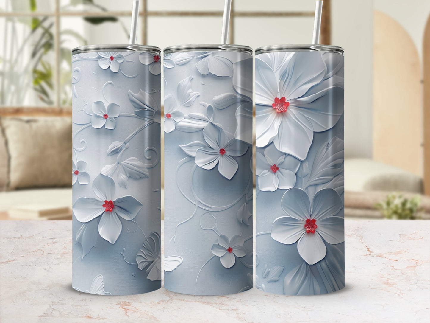 Three white floral tumblers with red flower centers on a marbled countertop.