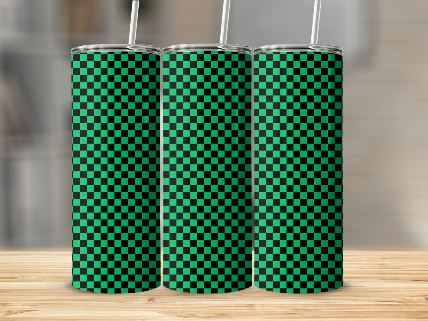 Three green and black checkerboard pattern tumblers with straws on a wooden surface.