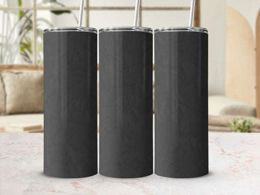 Three black tumblers with silver straws on a marble surface.