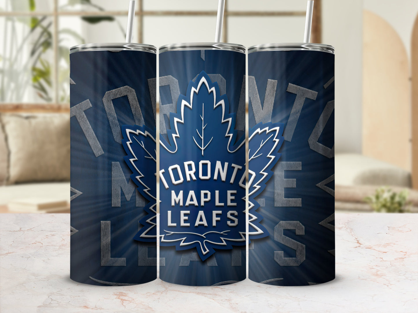 Three Toronto Maple Leafs tumblers with straws on a marbled surface.