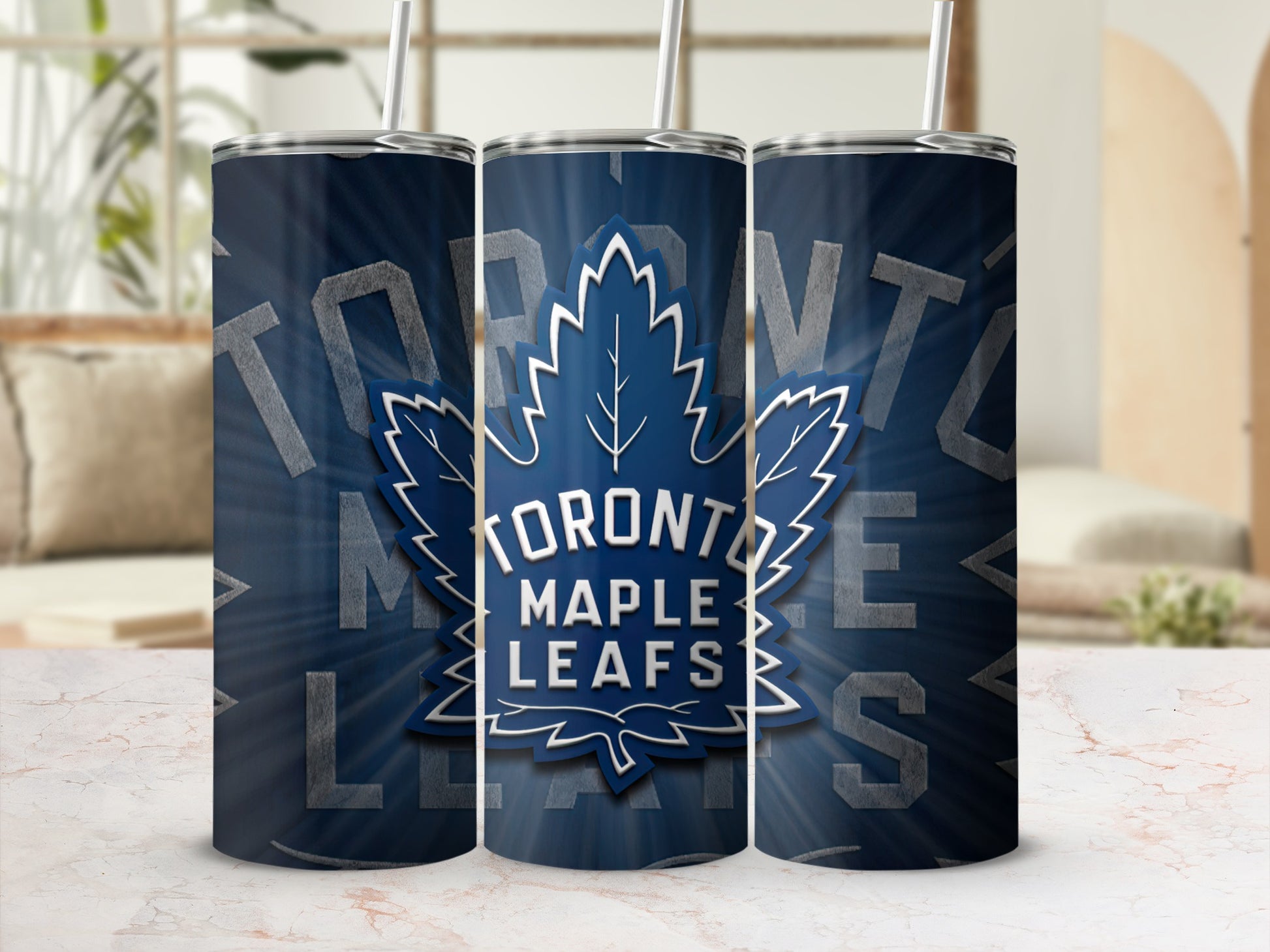 Three Toronto Maple Leafs tumblers with straws on a marbled surface.