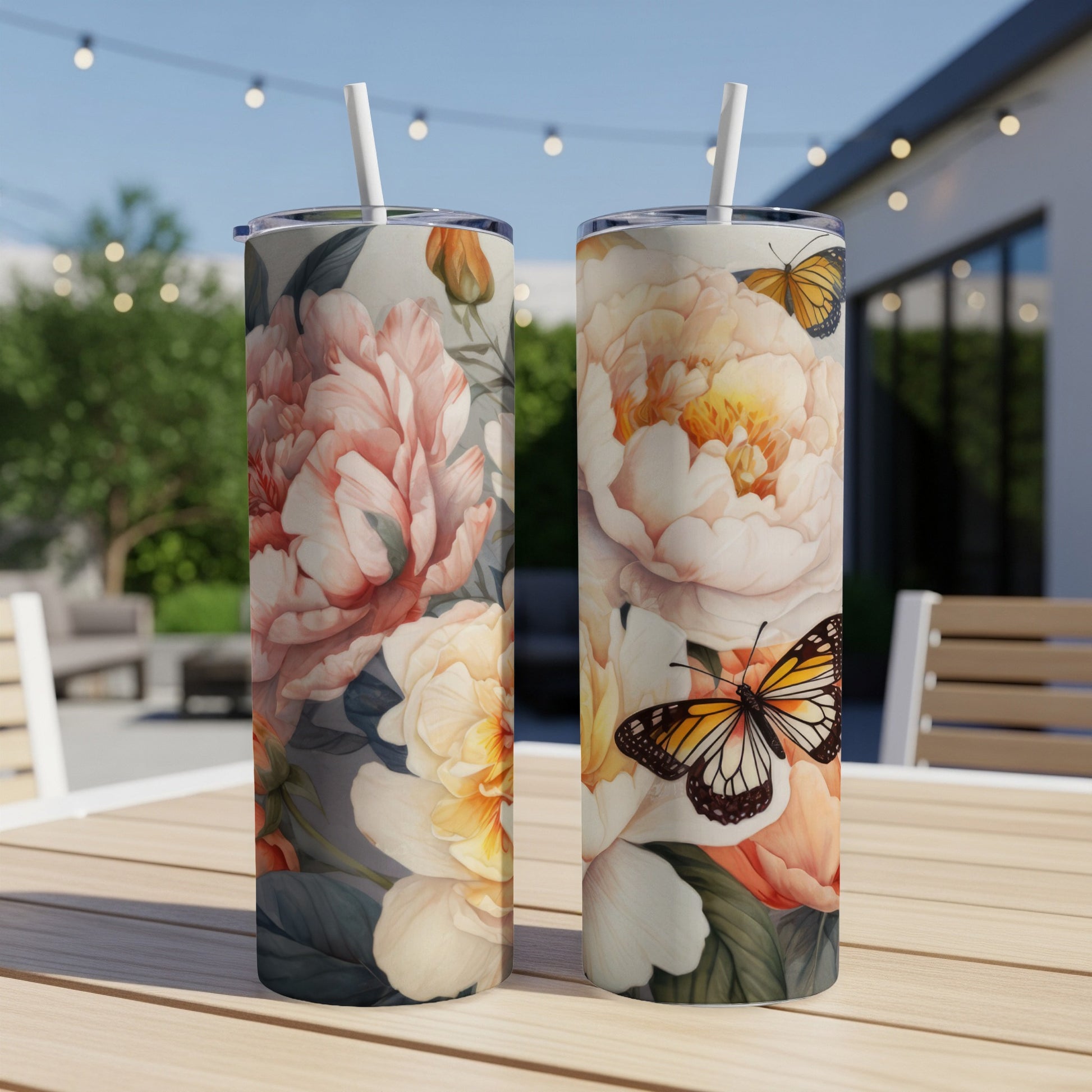 Two tumblers with floral and butterfly designs on a wooden table.
