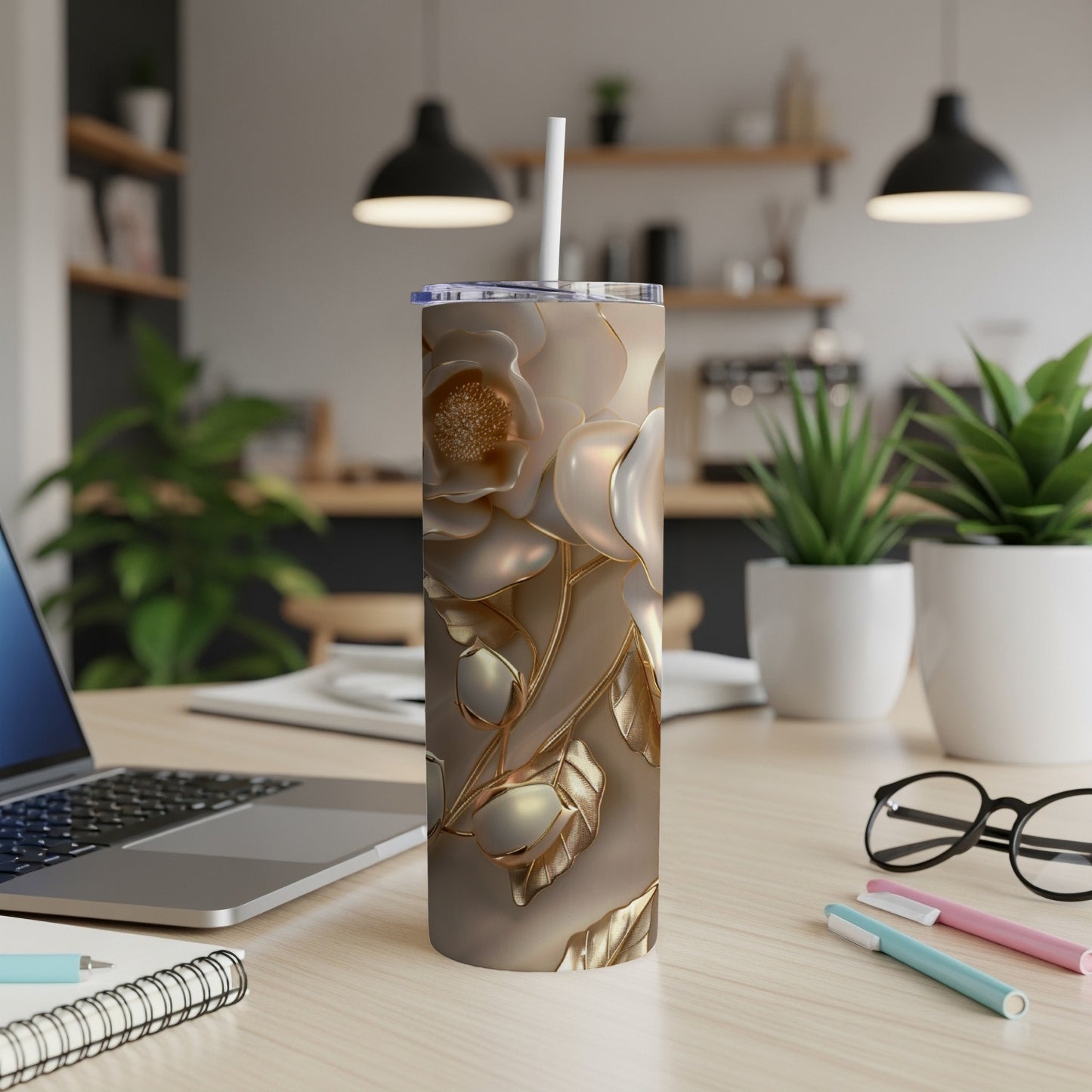 Tall, insulated tumbler with ornate gold floral design on a desk.