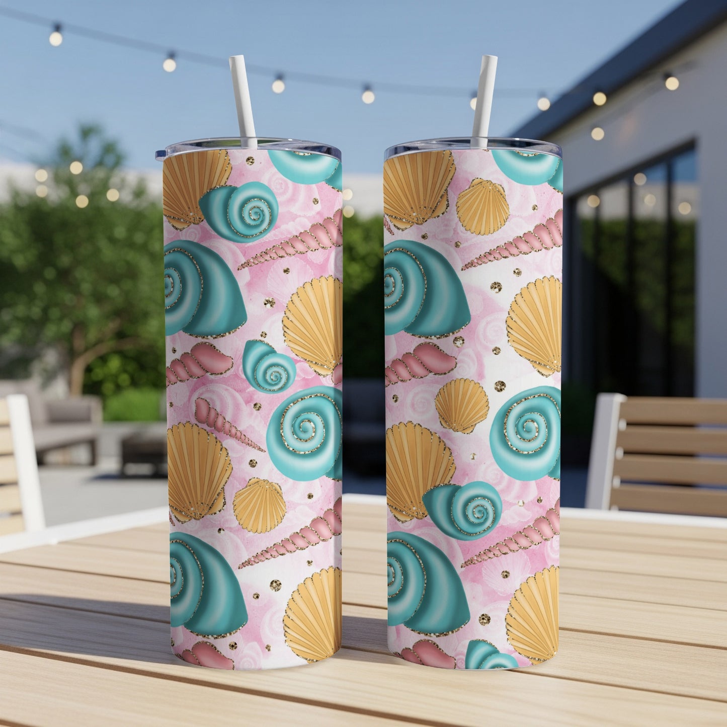 Two teal and pink seashells pattern tumblers with gold accents on a table.
