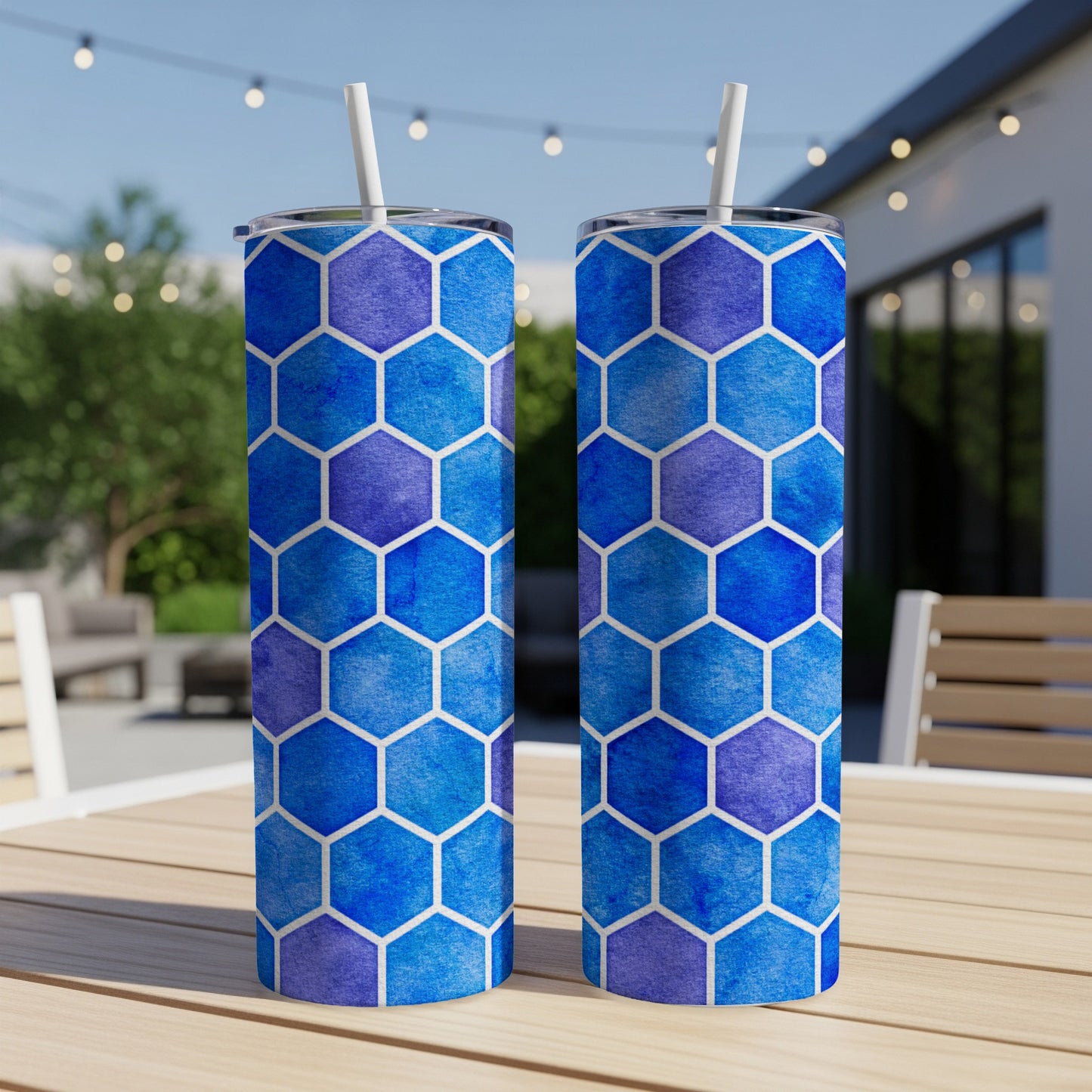 Two blue and purple gradient hexagonal pattern tumblers with white straws on a wooden table.