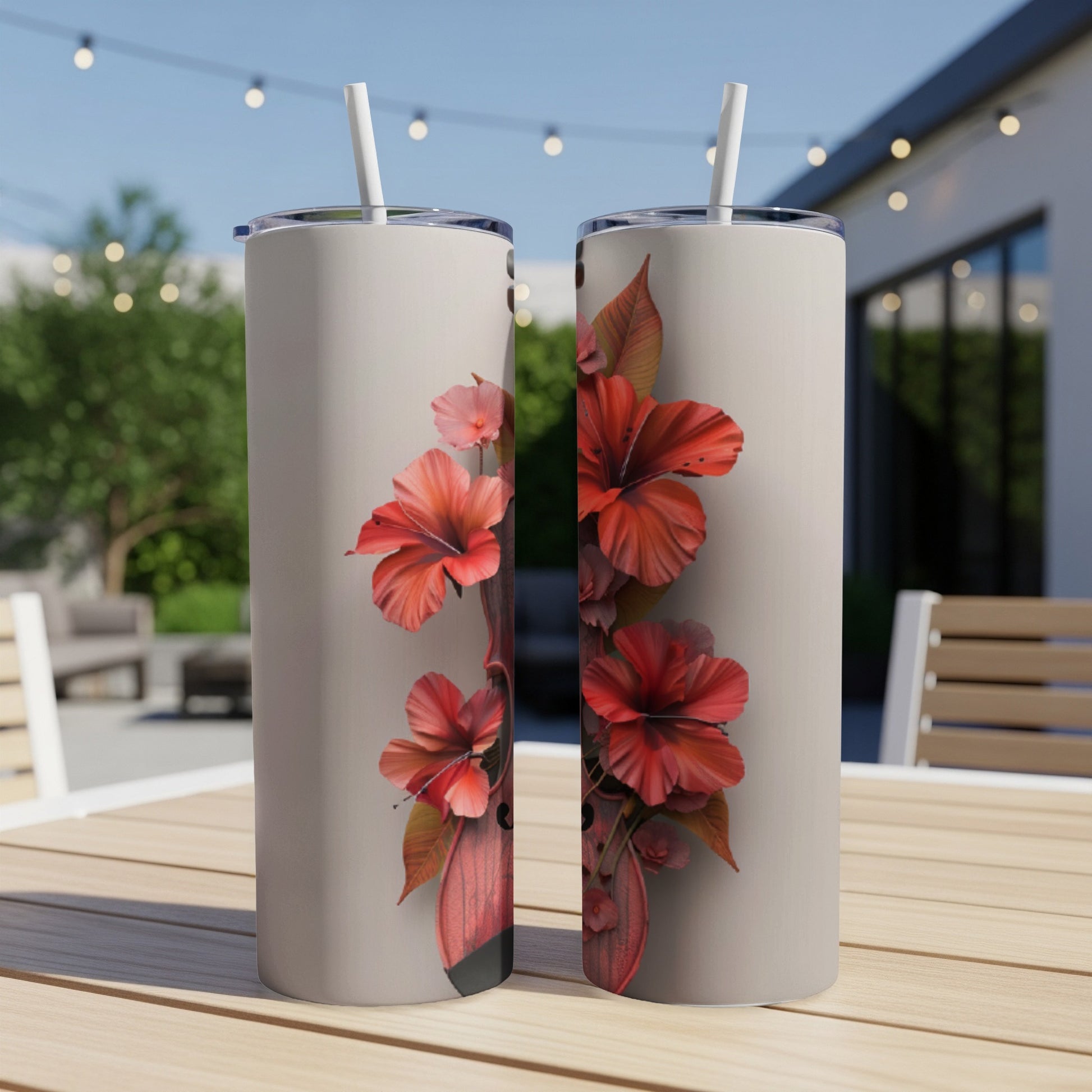 Two tumblers with a hibiscus floral design on a patio table.