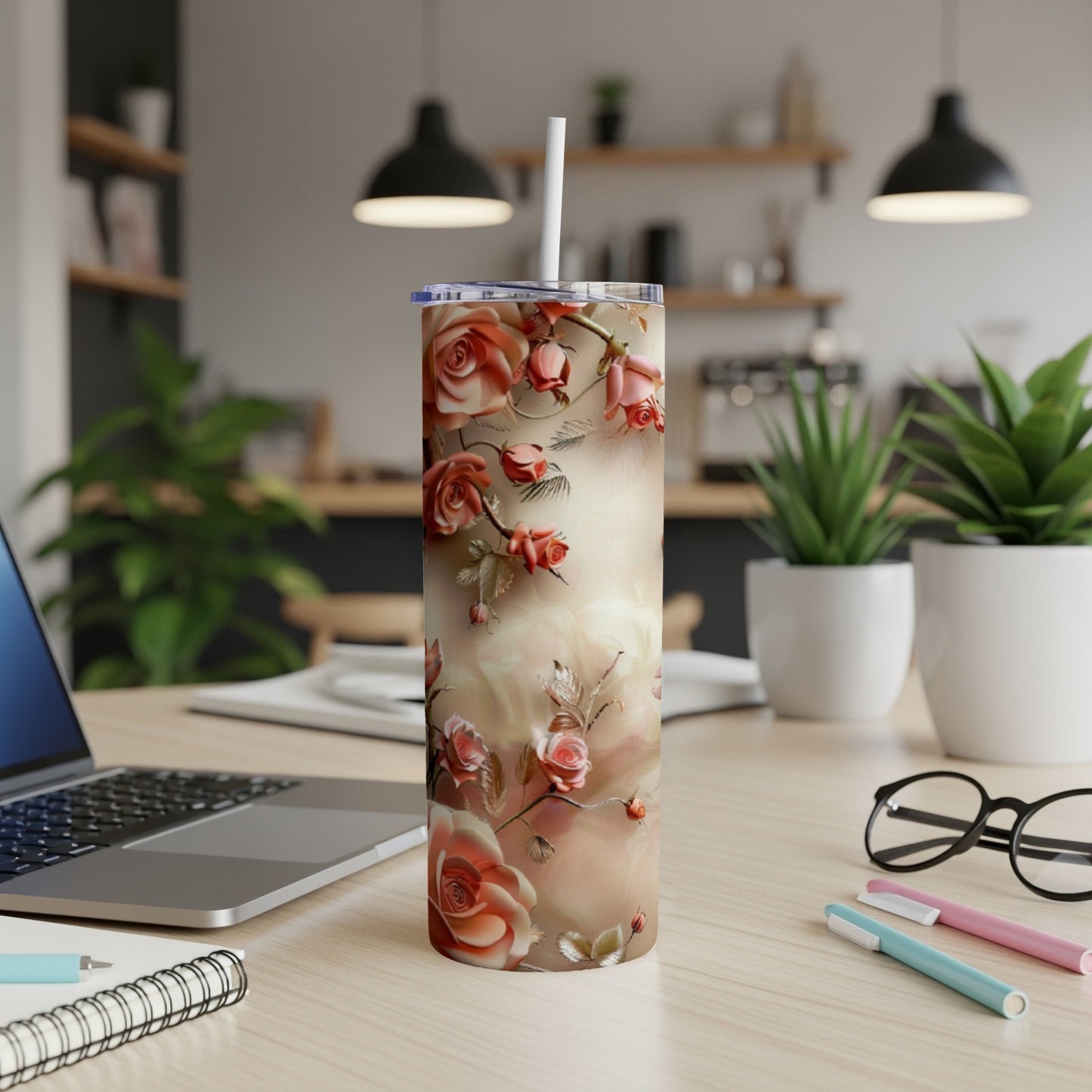 Floral tumbler with roses and a straw on a desk.