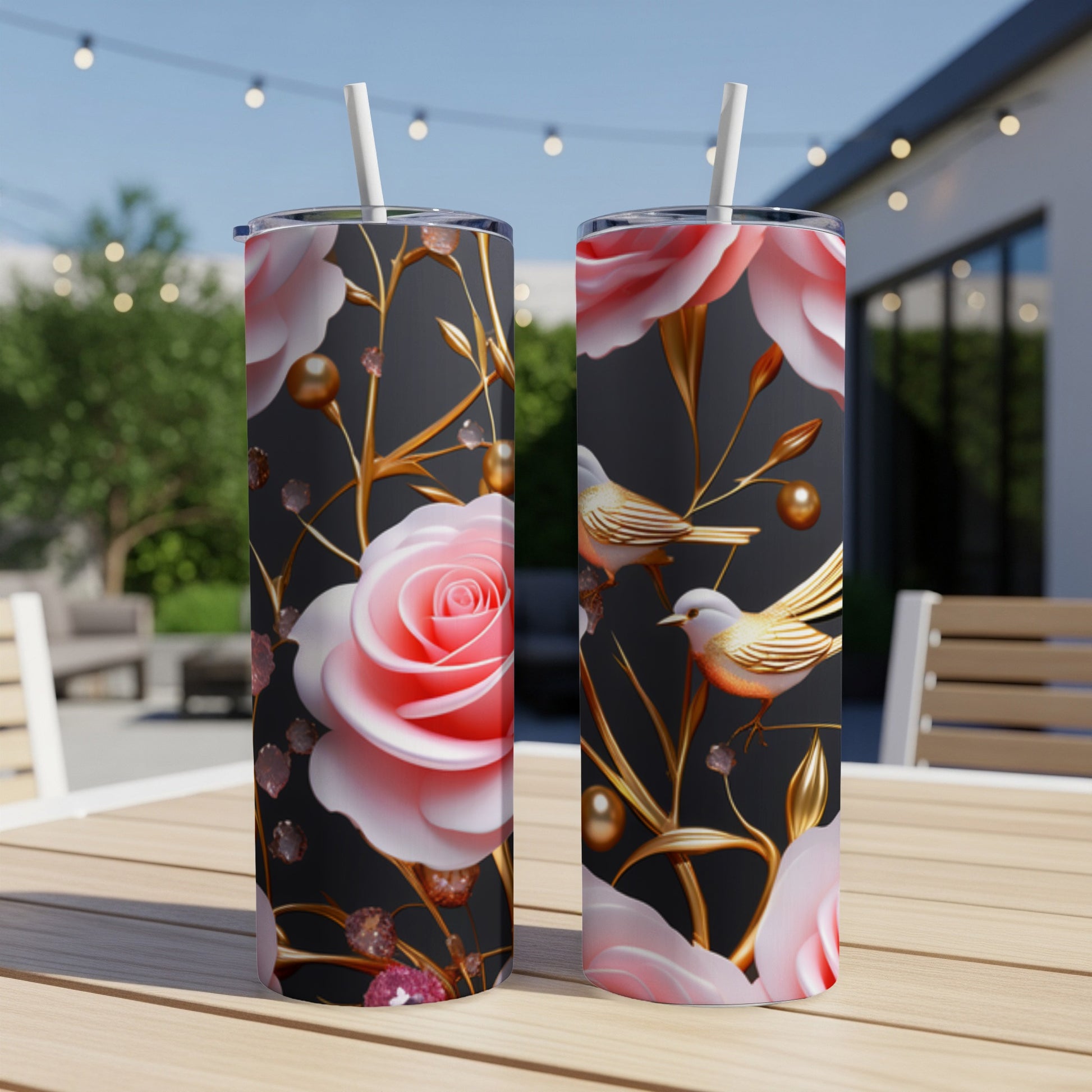 Two tumblers with pink roses, birds, and gold accents on a table.